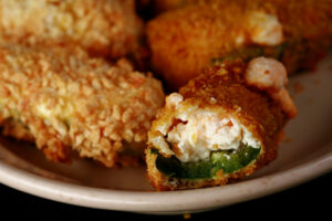 A close up view of air fryer gluten-free jalapeno poppers. One has a bite taken out of it.