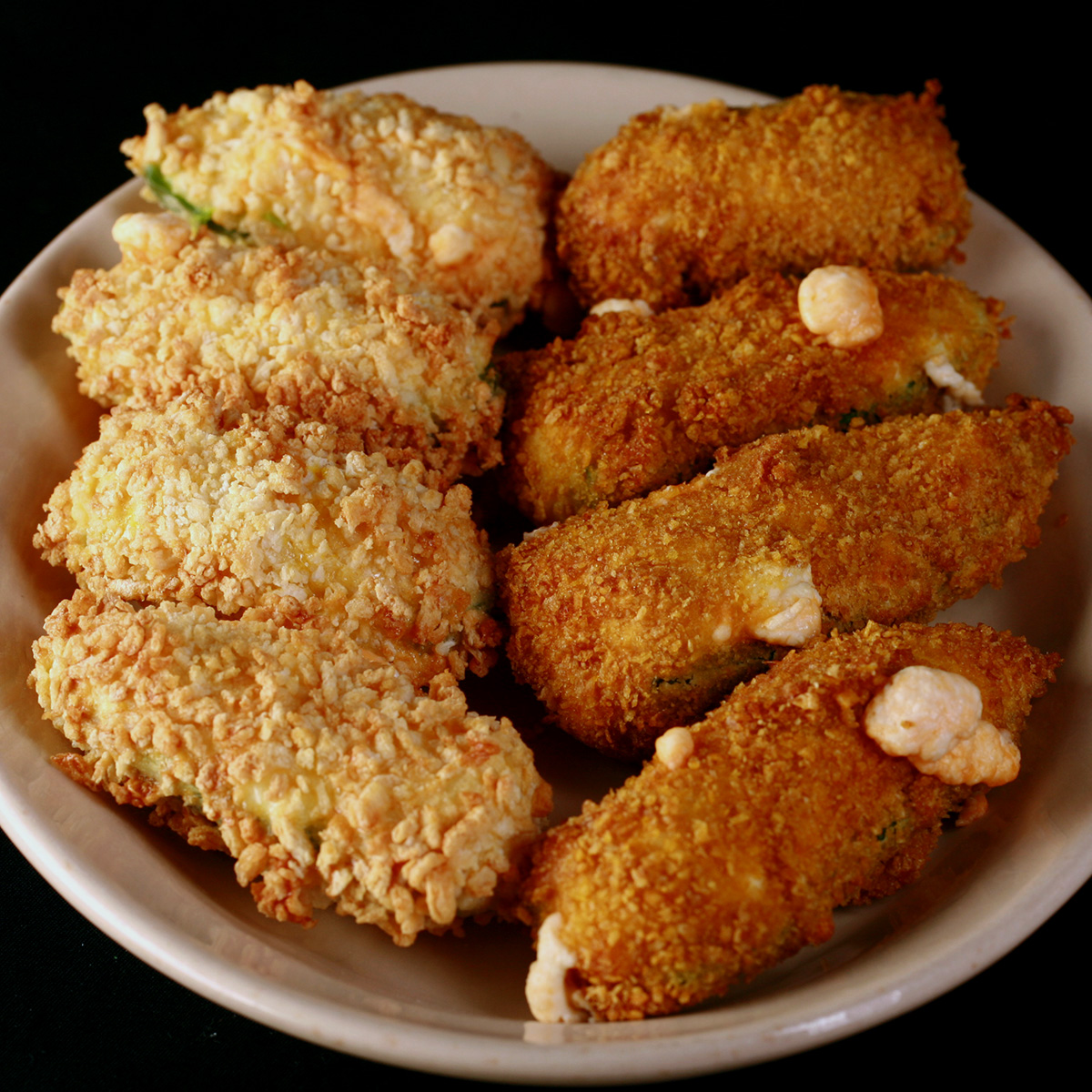 A small ivory colour plate holds two different types of gluten-free jalapeno poppers