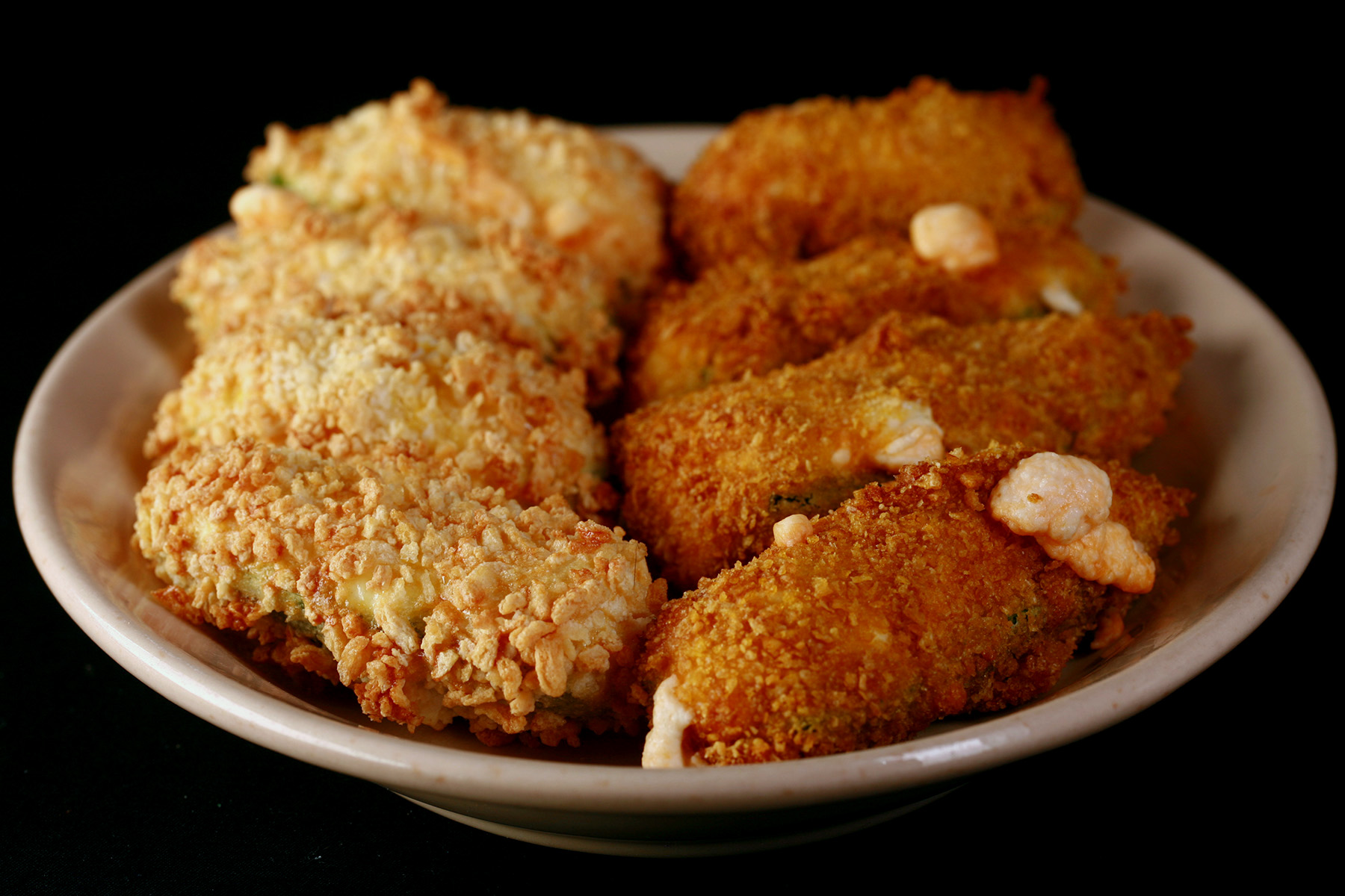 A small ivory colour plate holds two different types of gluten-free jalapeno poppers.