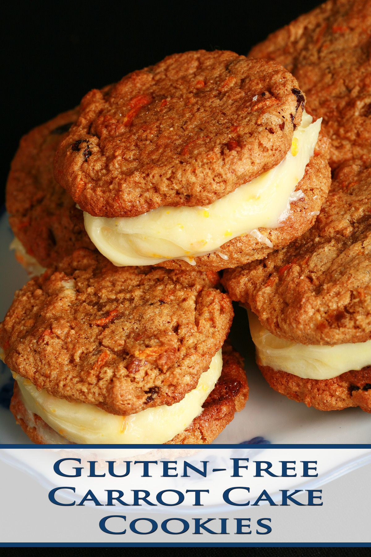 A small blue and white plate with a stack of gluten-free carrot cake sandwich cookies on it. The filling is ivory coloured and has flecks of orange zest throughout.