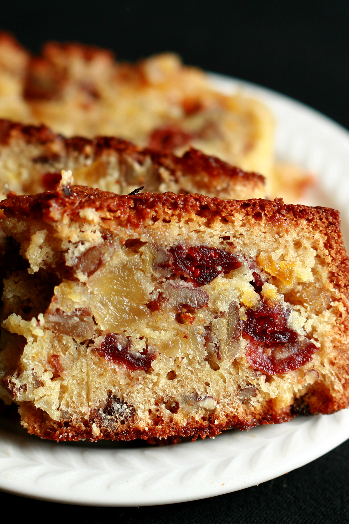 "Slices of gluten free fruitcake, on a small white plate. The cake is generously studded with dried - not candied - fruit.