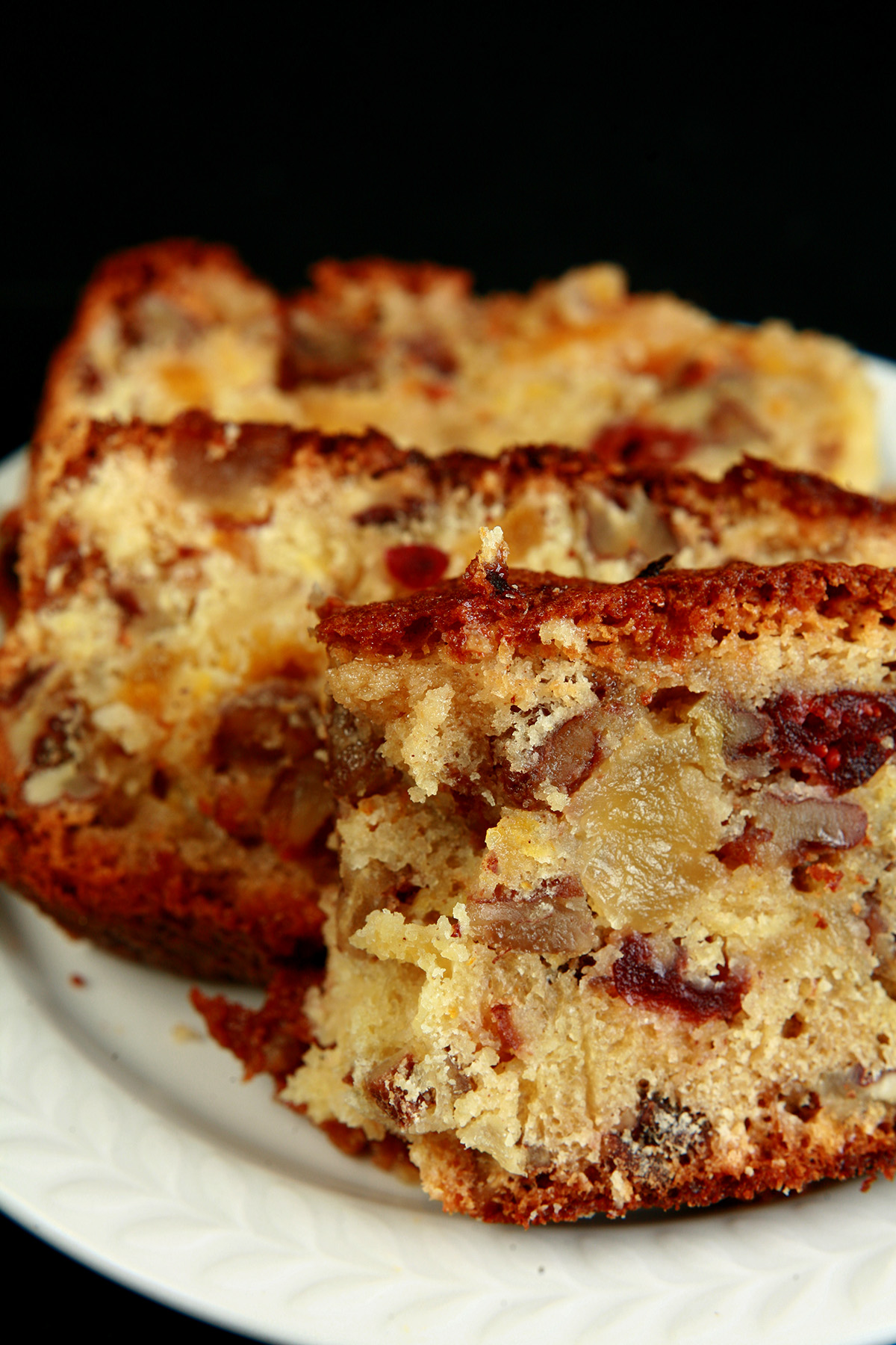 Slices of gluten-free fruitcake, on a small white plate. The cake is generously studded with dried - not candied - fruit.