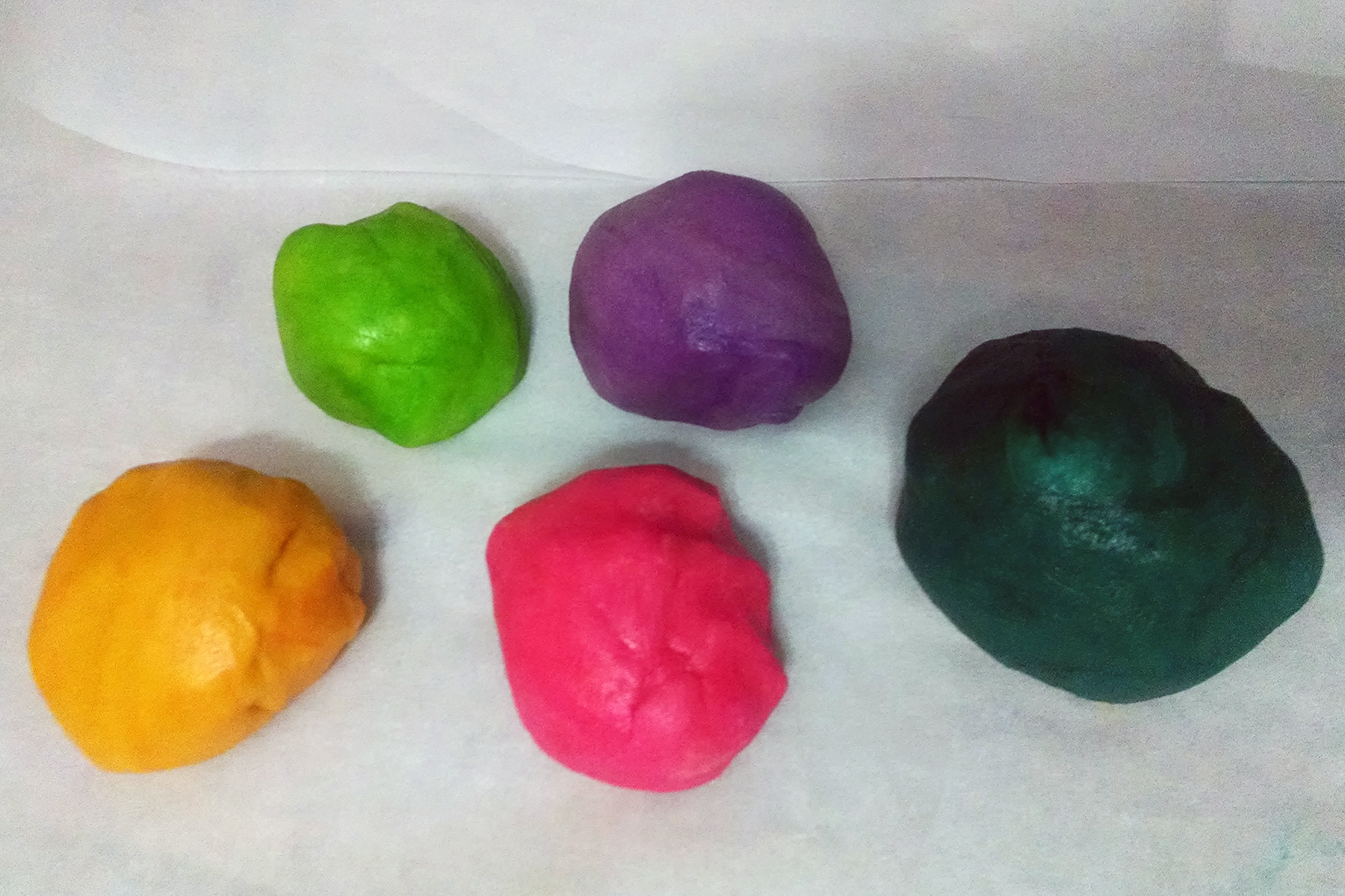 5 balls of brightly coloured cookie dough, in pink, yellow, green, purple, and teal.