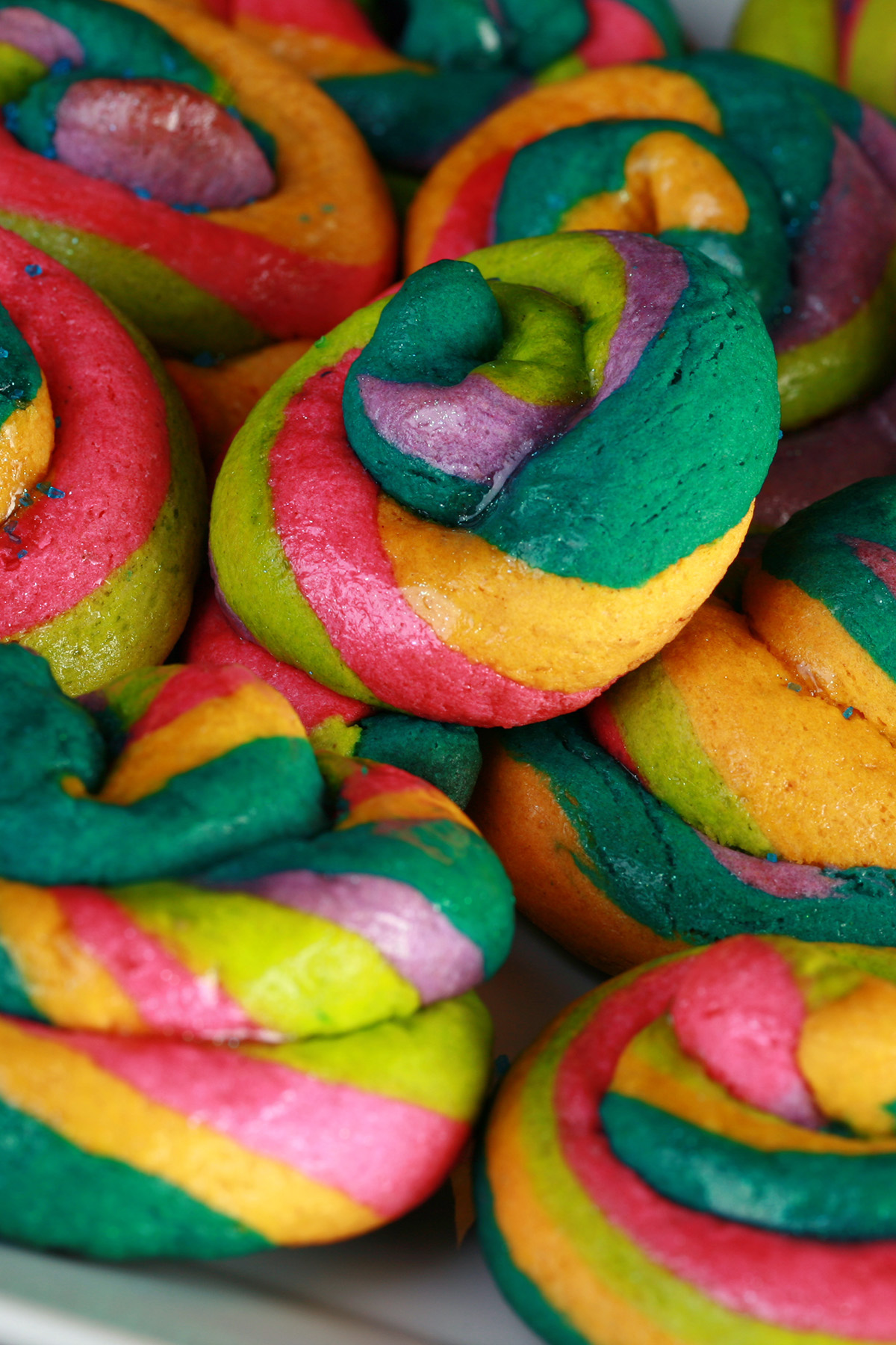 A close up view of a pile of gluten-free unicorn poop cookies.  They are brightly coloured cookie "poops" made from brightly coloured twists of cookie dough.