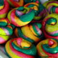 A close up view of a pile of gluten-free unicorn poop cookies. They are brightly coloured cookie "poops" made from brightly coloured twists of cookie dough.