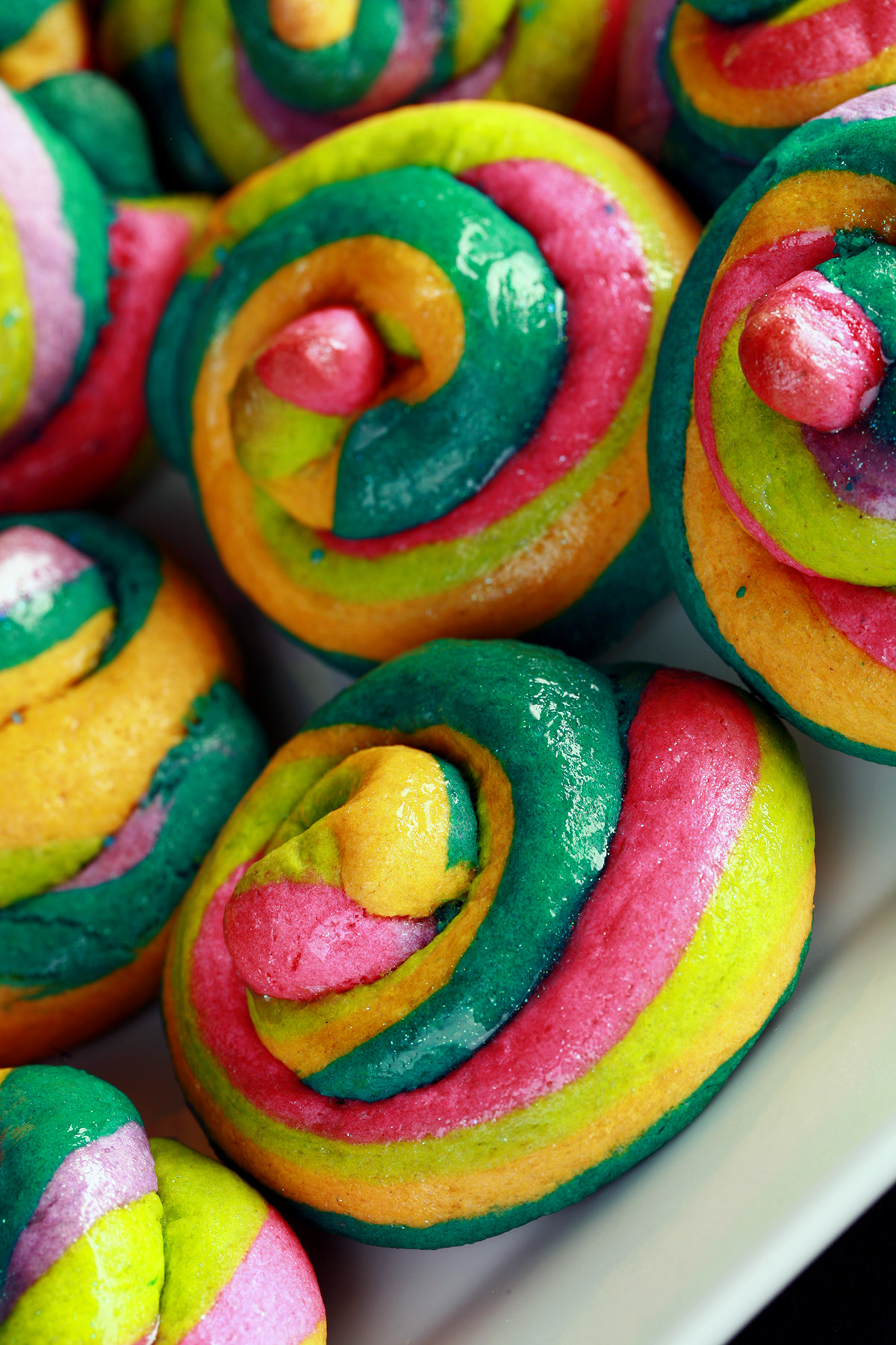 A close up view of a pile of gluten-free unicorn poop cookies.  They are brightly coloured cookie "poops" made from brightly coloured twists of cookie dough.