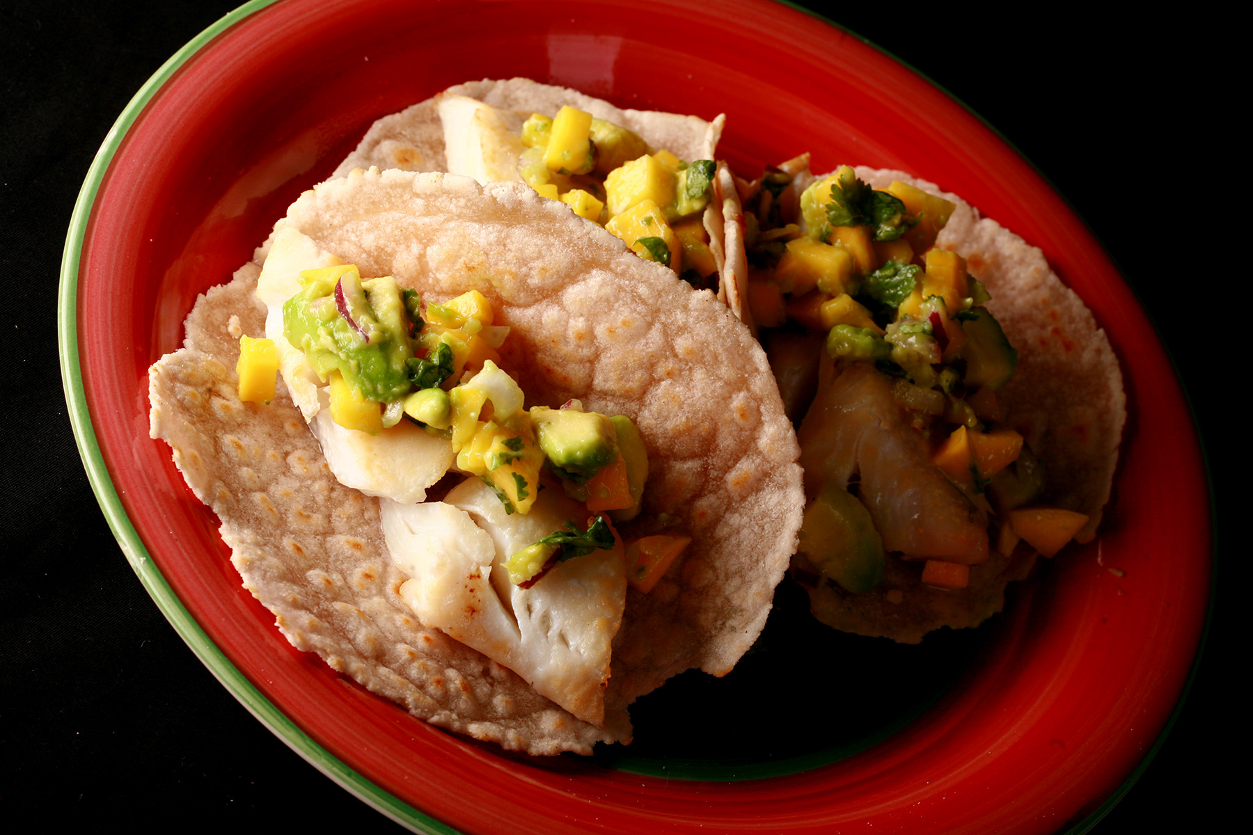 Cassava flour paleo fish tacos, with mango salsa, on a red plate.