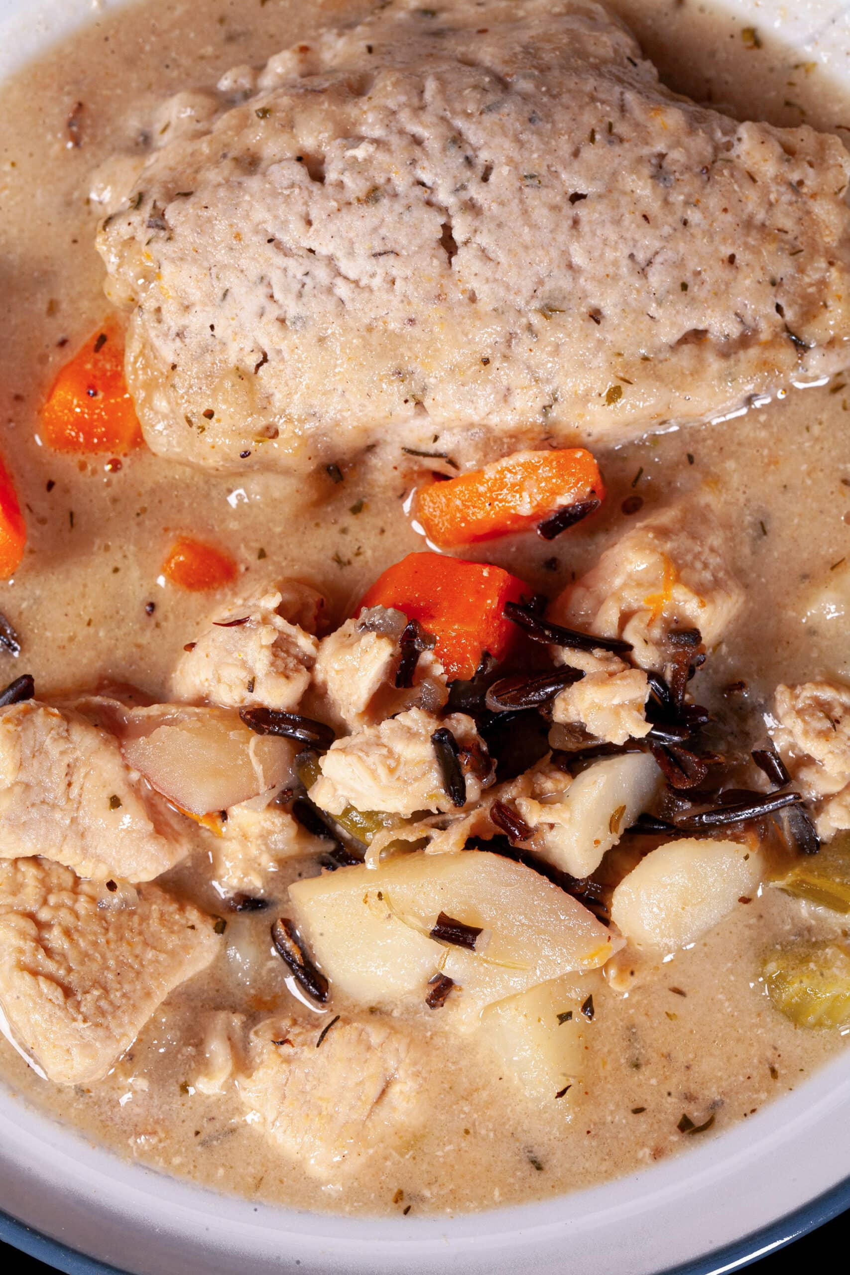 A bowl of gluten free creamy chicken wild rice soup with dumplings.