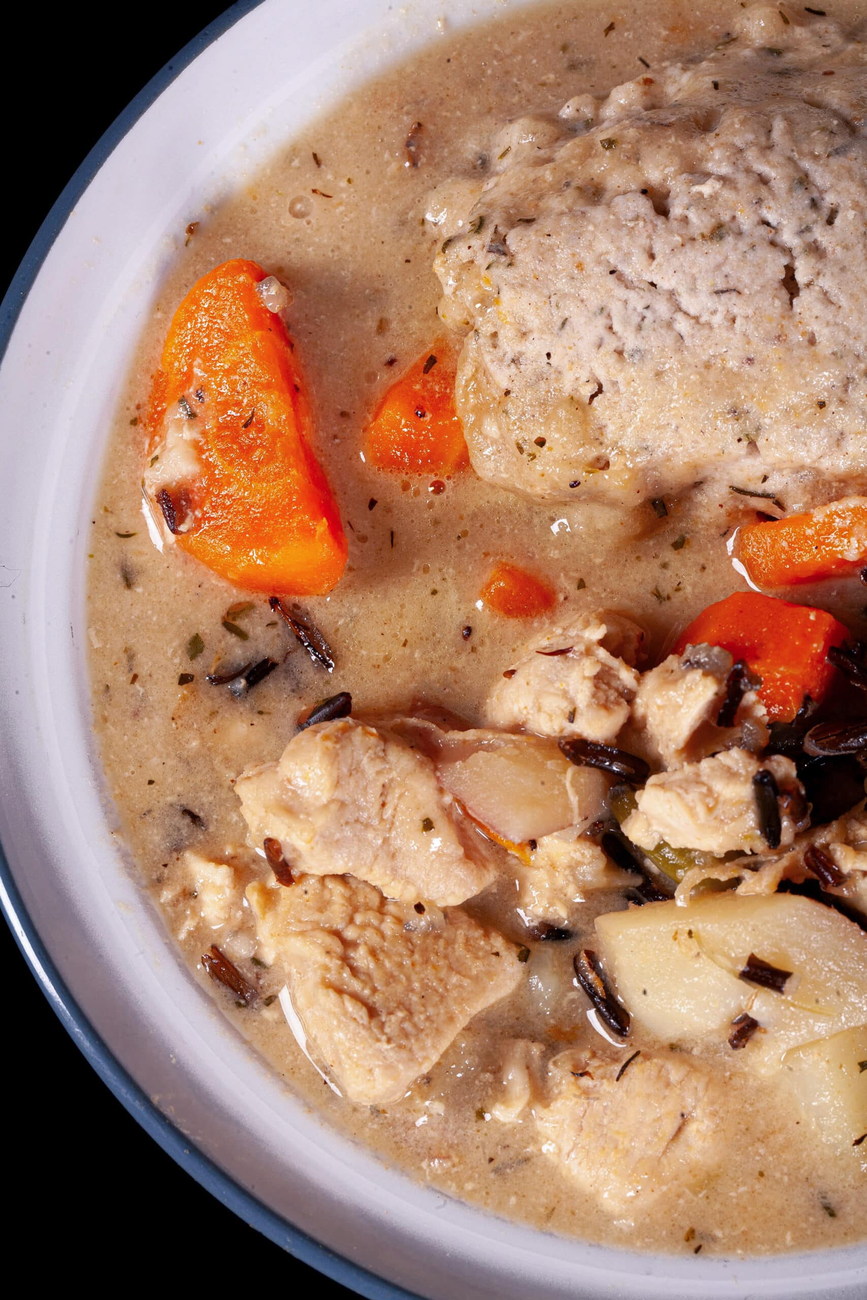A bowl of gluten free creamy chicken wild rice soup with dumplings.