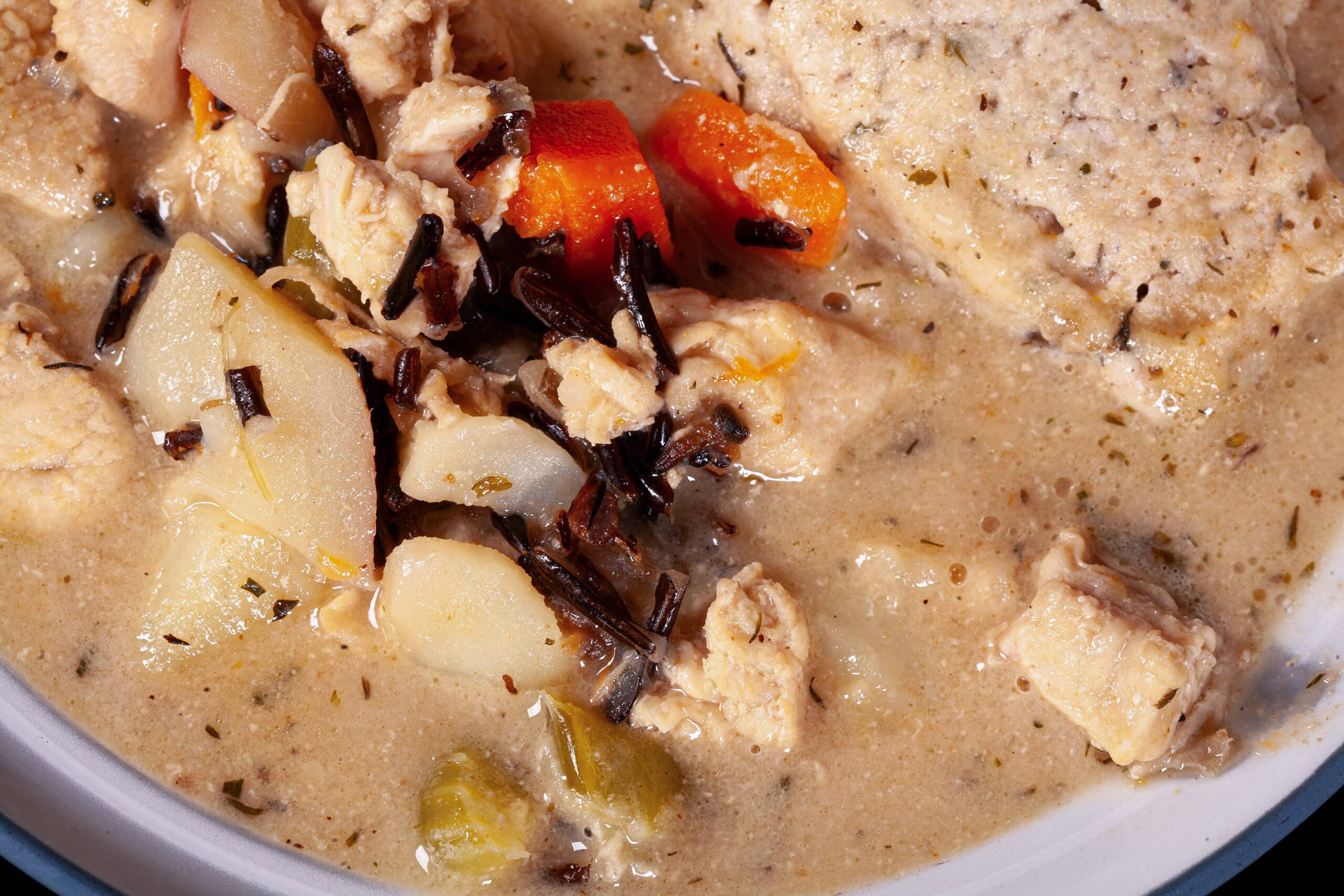 A bowl of gluten free creamy chicken wild rice soup with dumplings.
