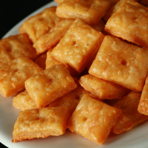 A pile of gluten-Free Cheez-its - little square gluten-free cheese crackers.