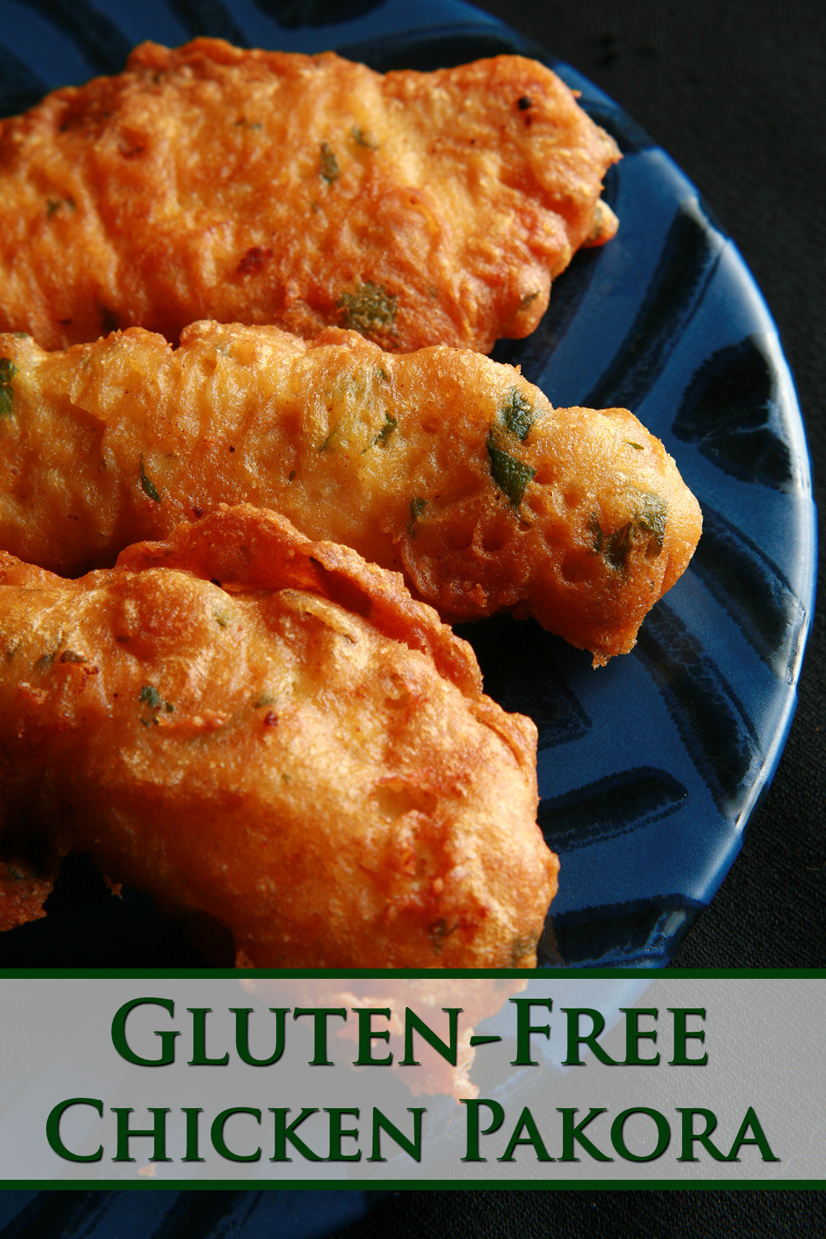 Several strips of gluten-free chicken pakora on a blue plate. They are golden deep fried, with flecks of green cilantro.