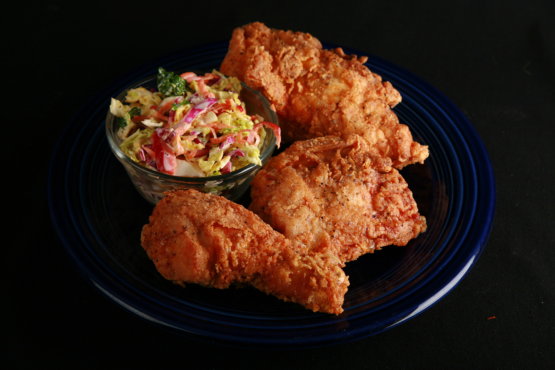 3 pieces of gluten-free fried chicken on a plate, next to a small bowl of colourful coleslaw.