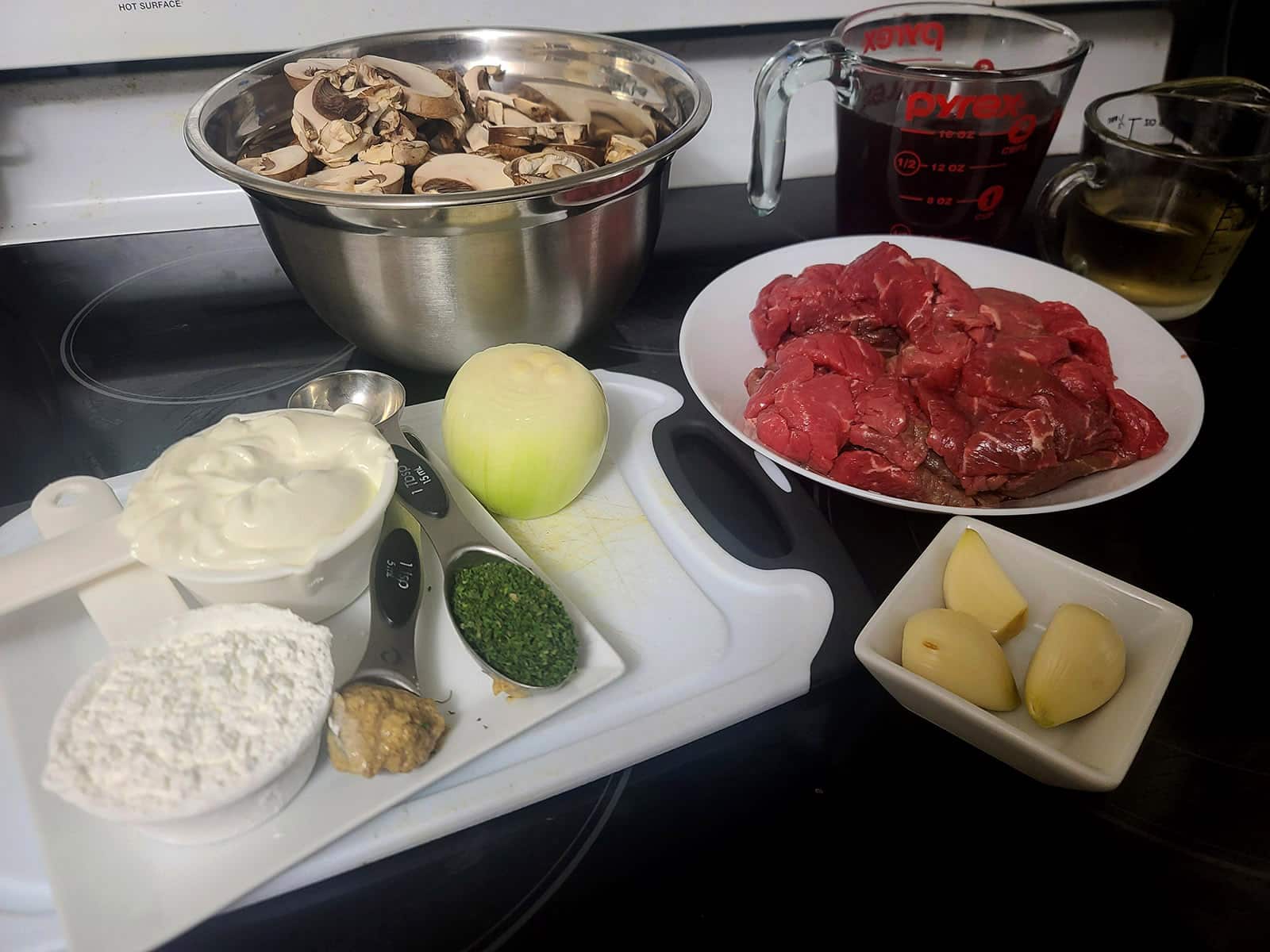 All of the ingredients for the beef stroganoff, laid out on a stove top.