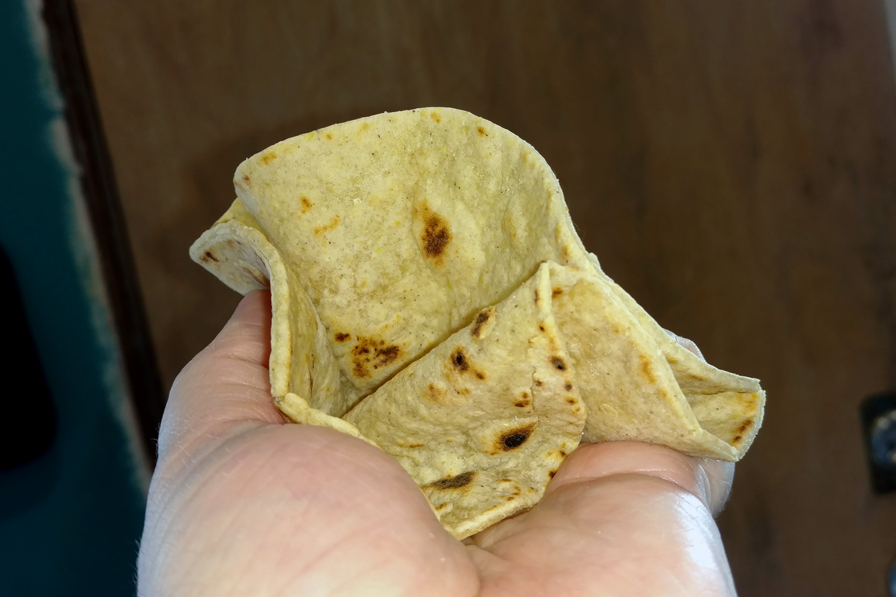 A hand crumples a tortilla, without any tearing.