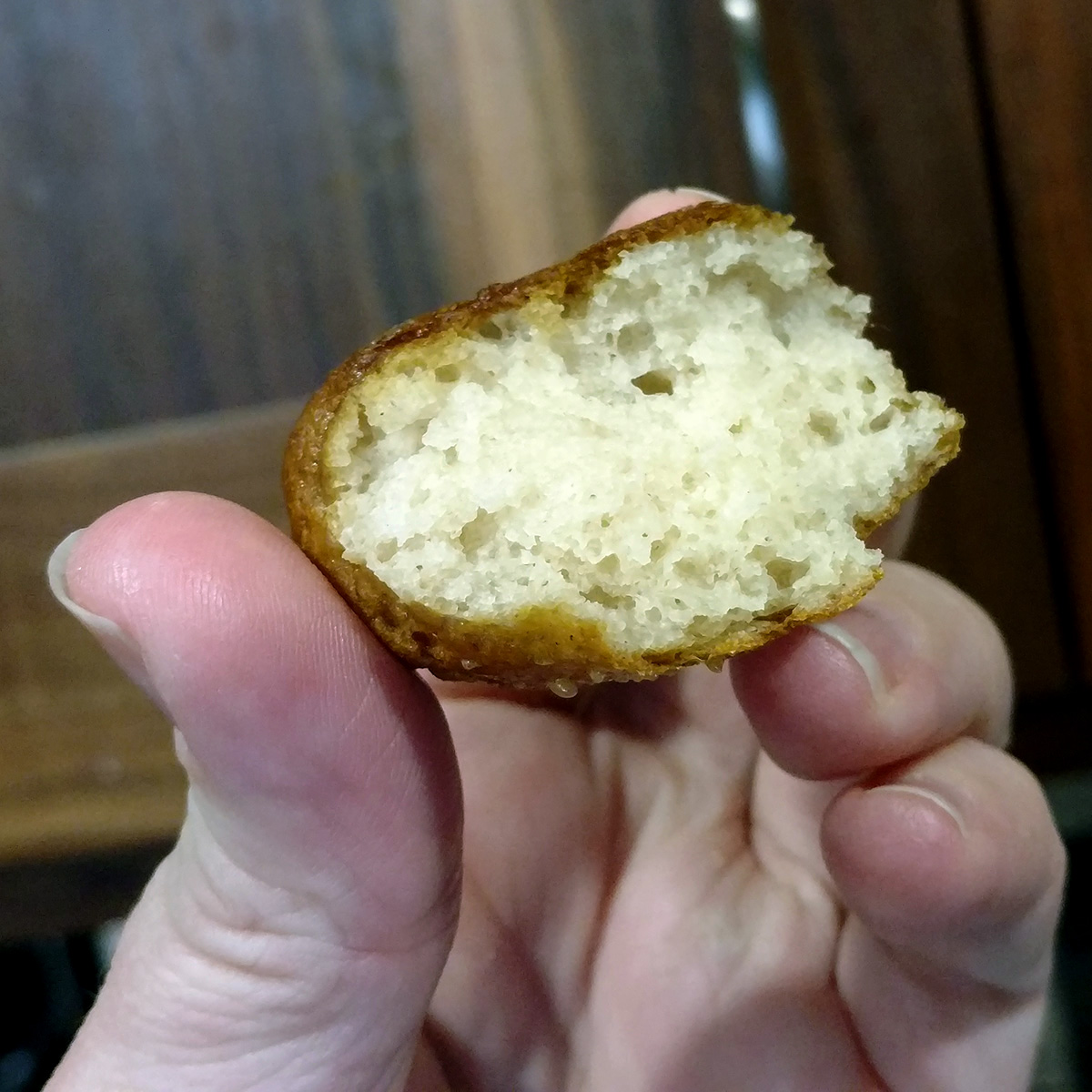 A hand holds a small chunk of gluten-free soft pretzel.
