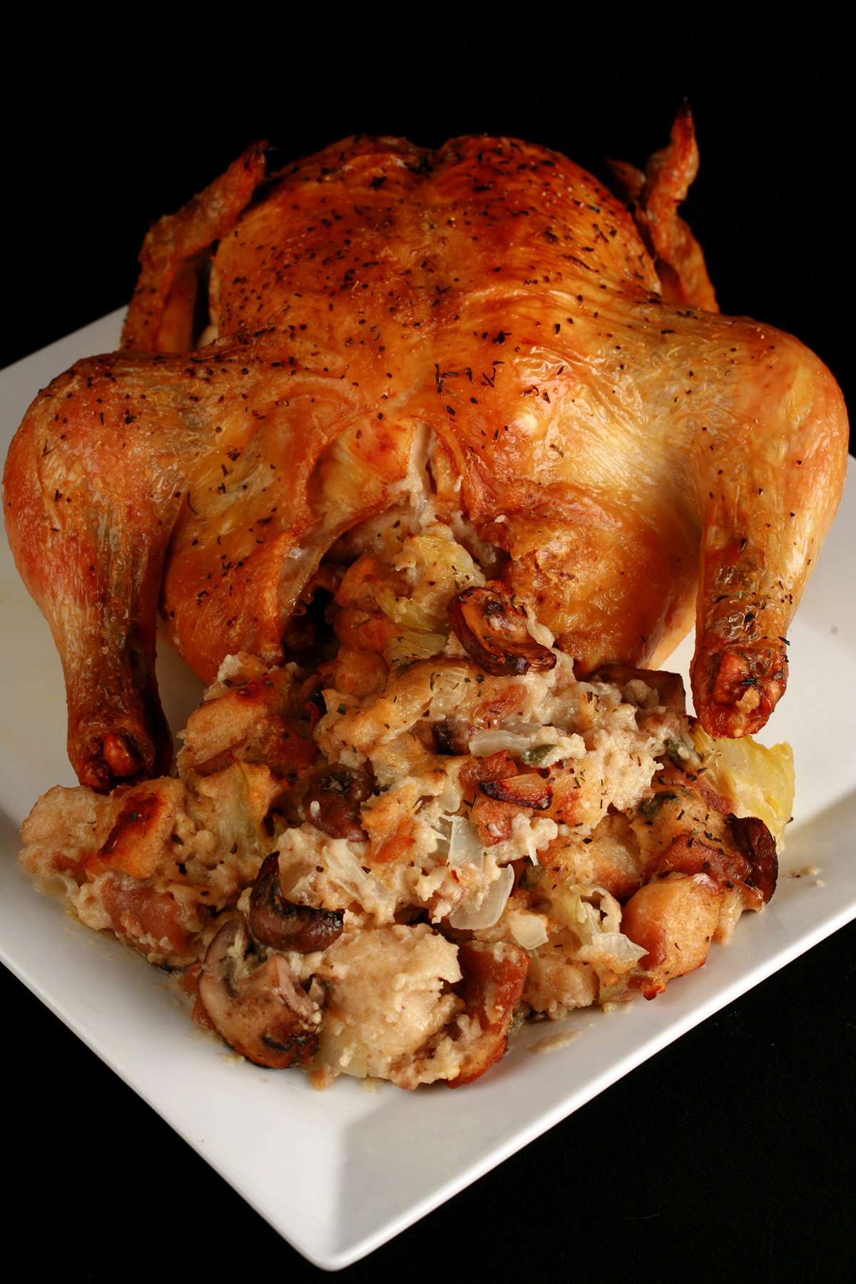 A small roasted turkey on a platter, with gluten-free stuffing spilling out from it.