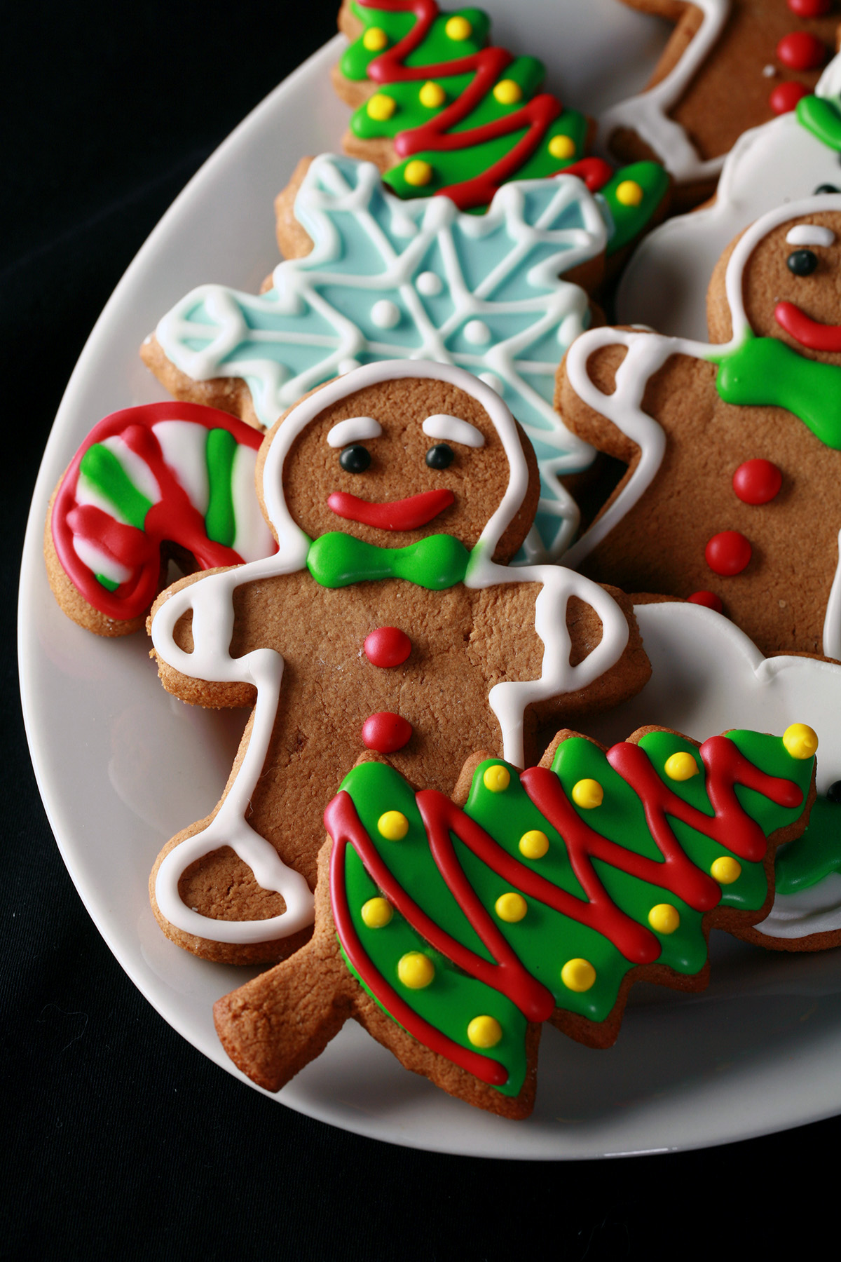 A plate of gluten-free gingerbread cookies, in various shapes, decorated with colourful royal icing.
