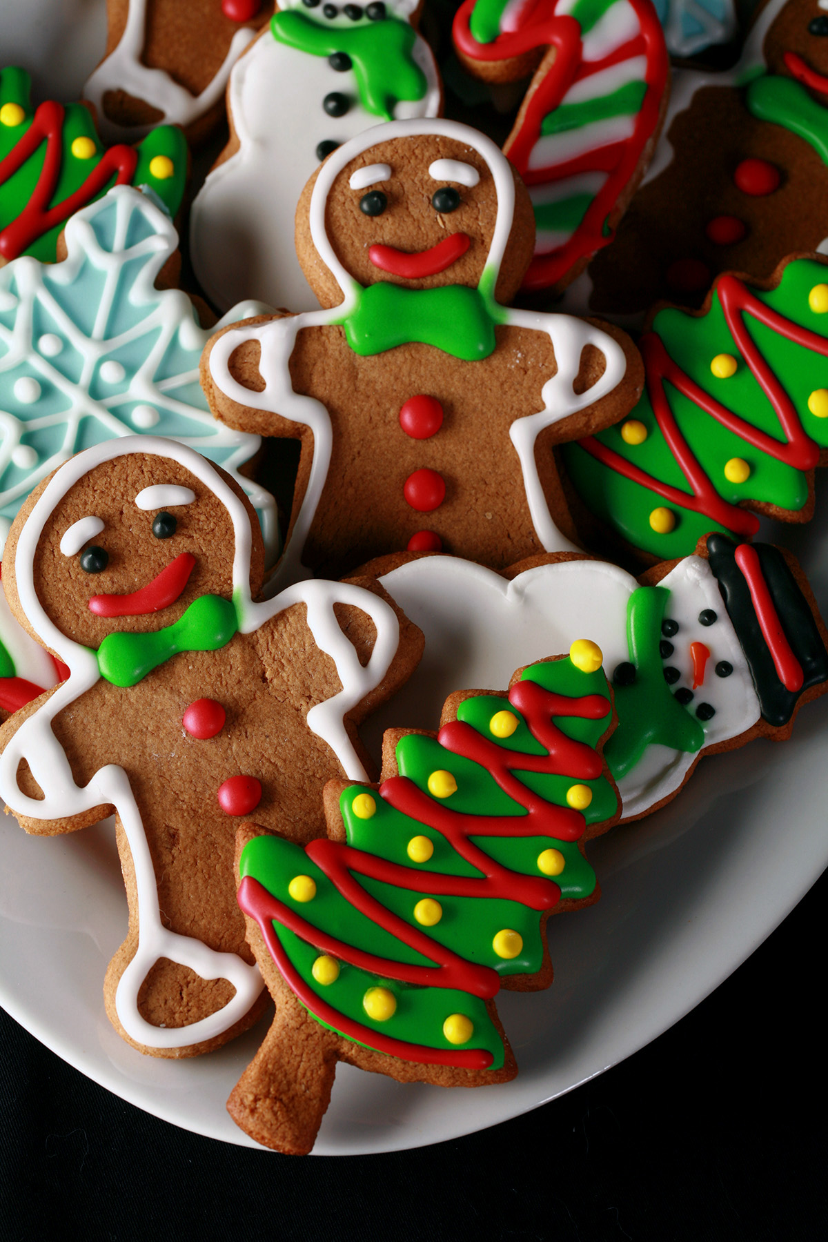 A plate of gluten-free gingerbread cookies, in various shapes, decorated with colourful royal icing.