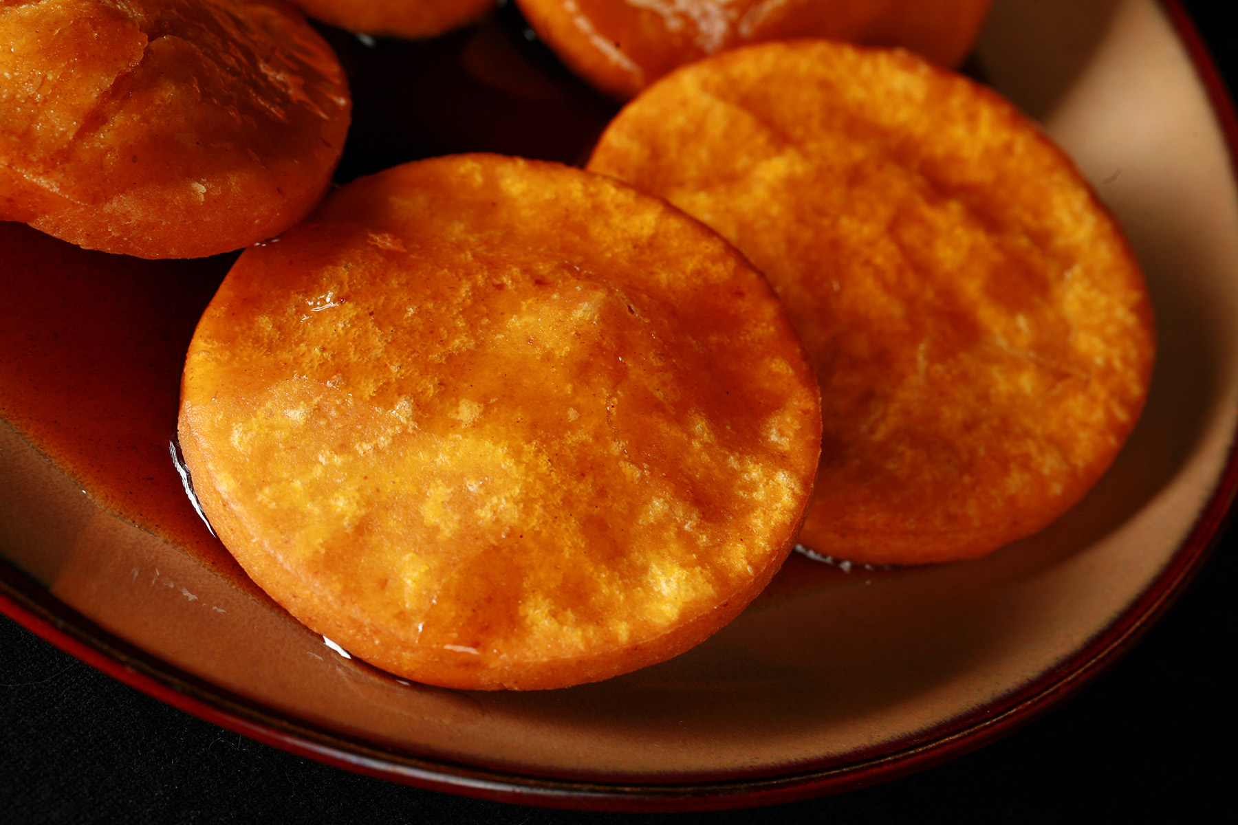 A plate of gluten free sopaipilla pasadas, with sauce drizzled over them.