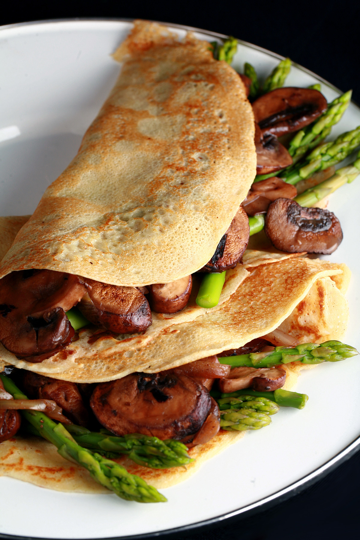Two gluten free crepes with mushroom and asparagus filling.