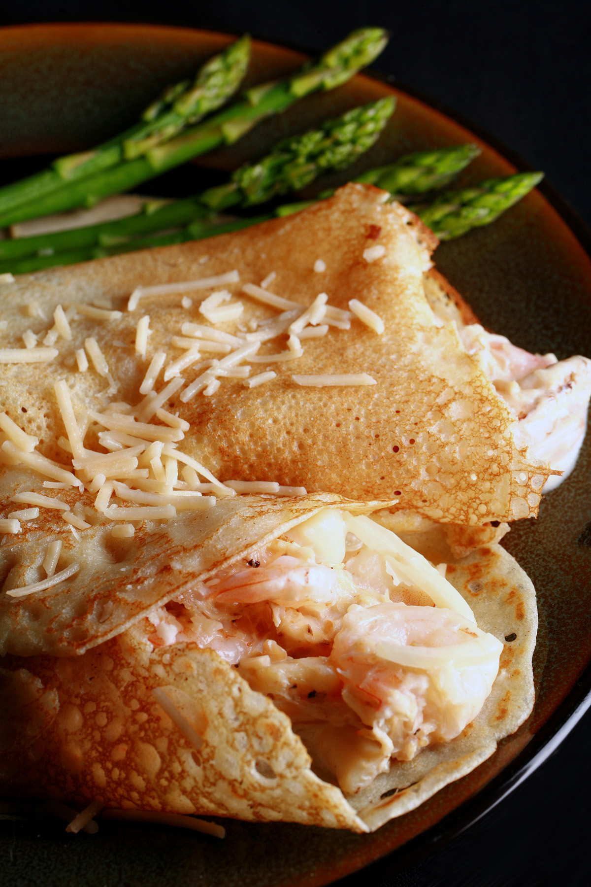 2 Gluten free seafood crepes with asparagus spears on the side.