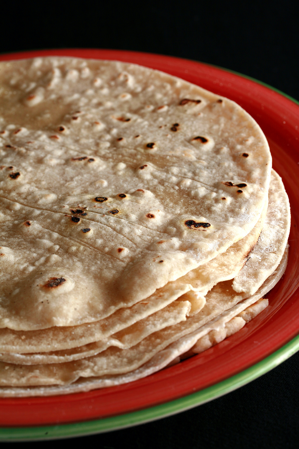 A stack of gluten free flour tortillas on a red plate.