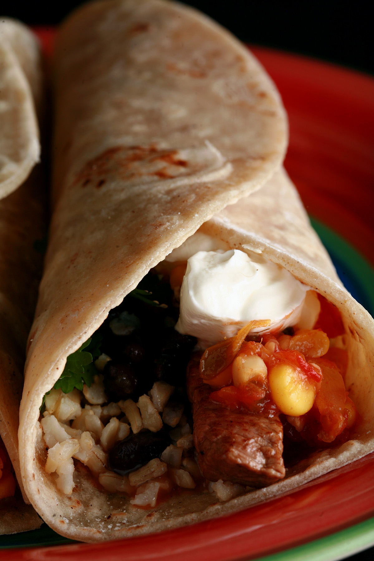 A close up view of a gluten free burrito on a red plate.