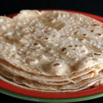 A stack of gluten free tortillas on a red plate.