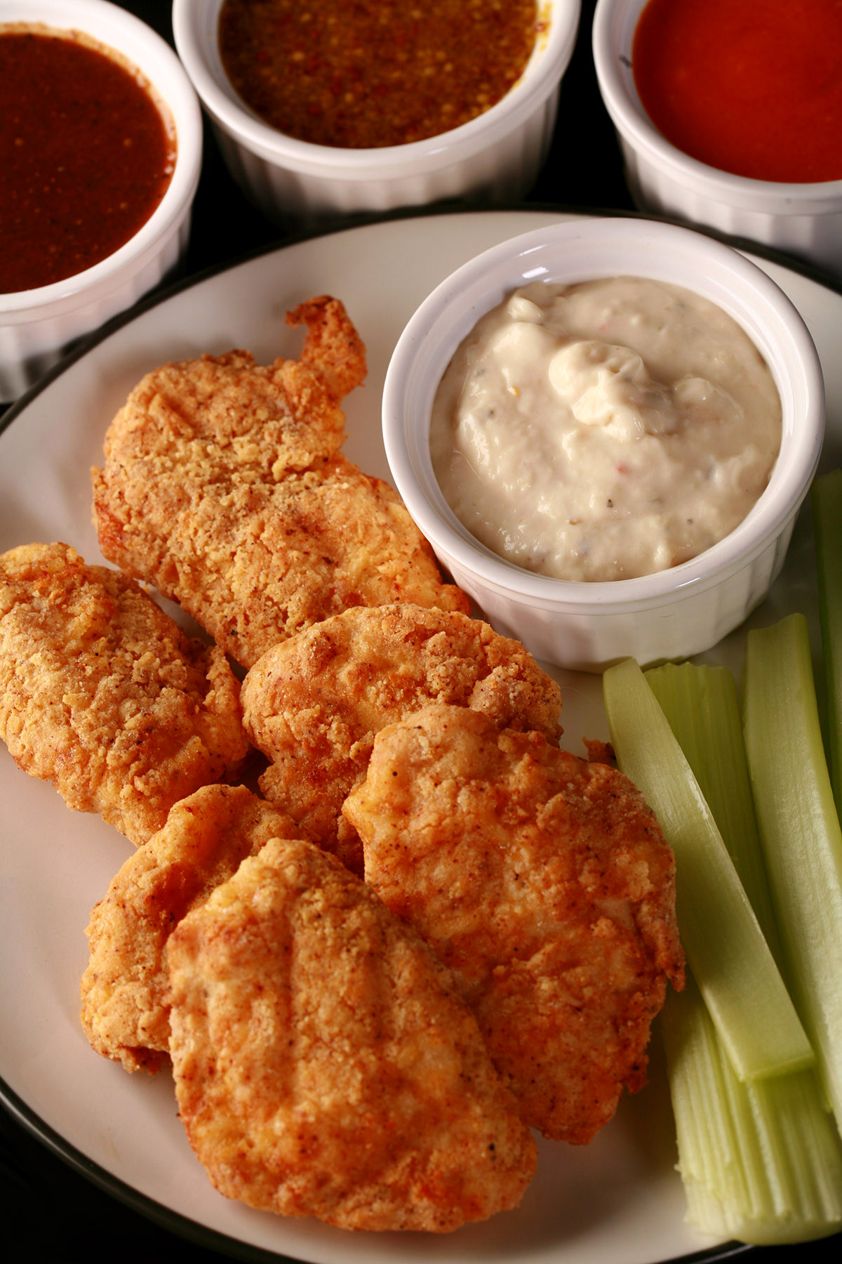 A plate of air fried gluten-free chicken nuggets, celery, and dip.