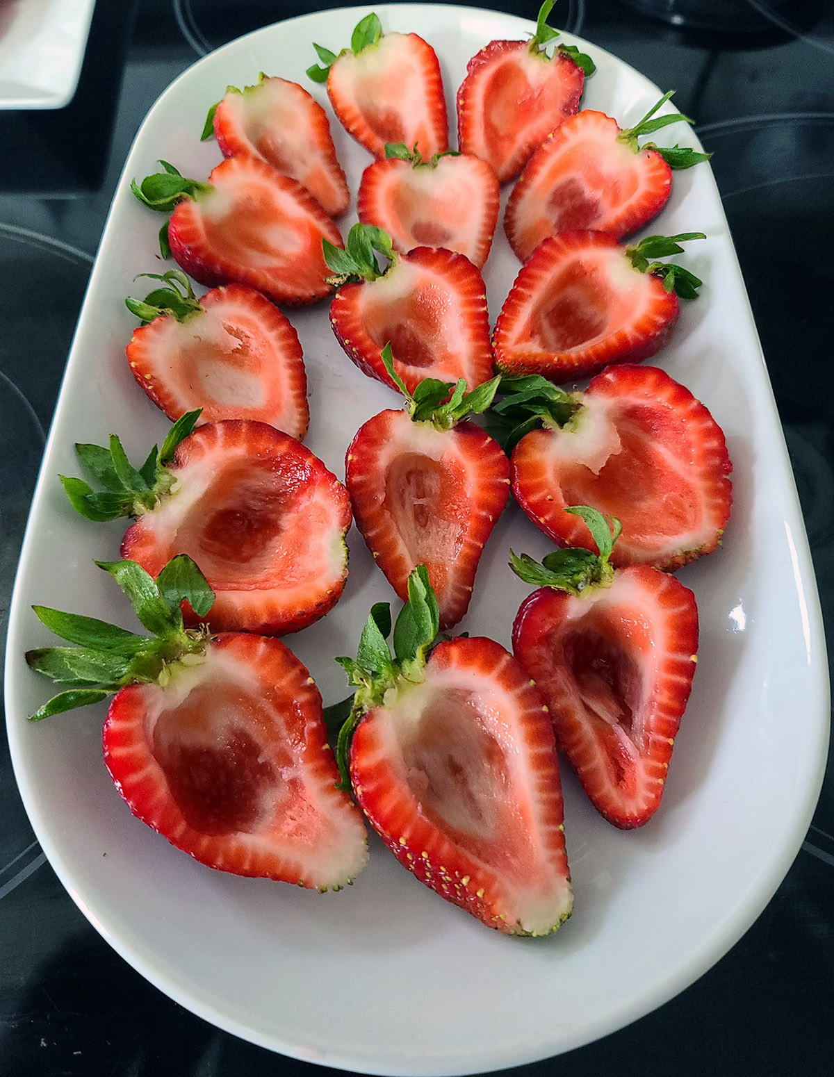 A tray of halved and scooped strawberries.