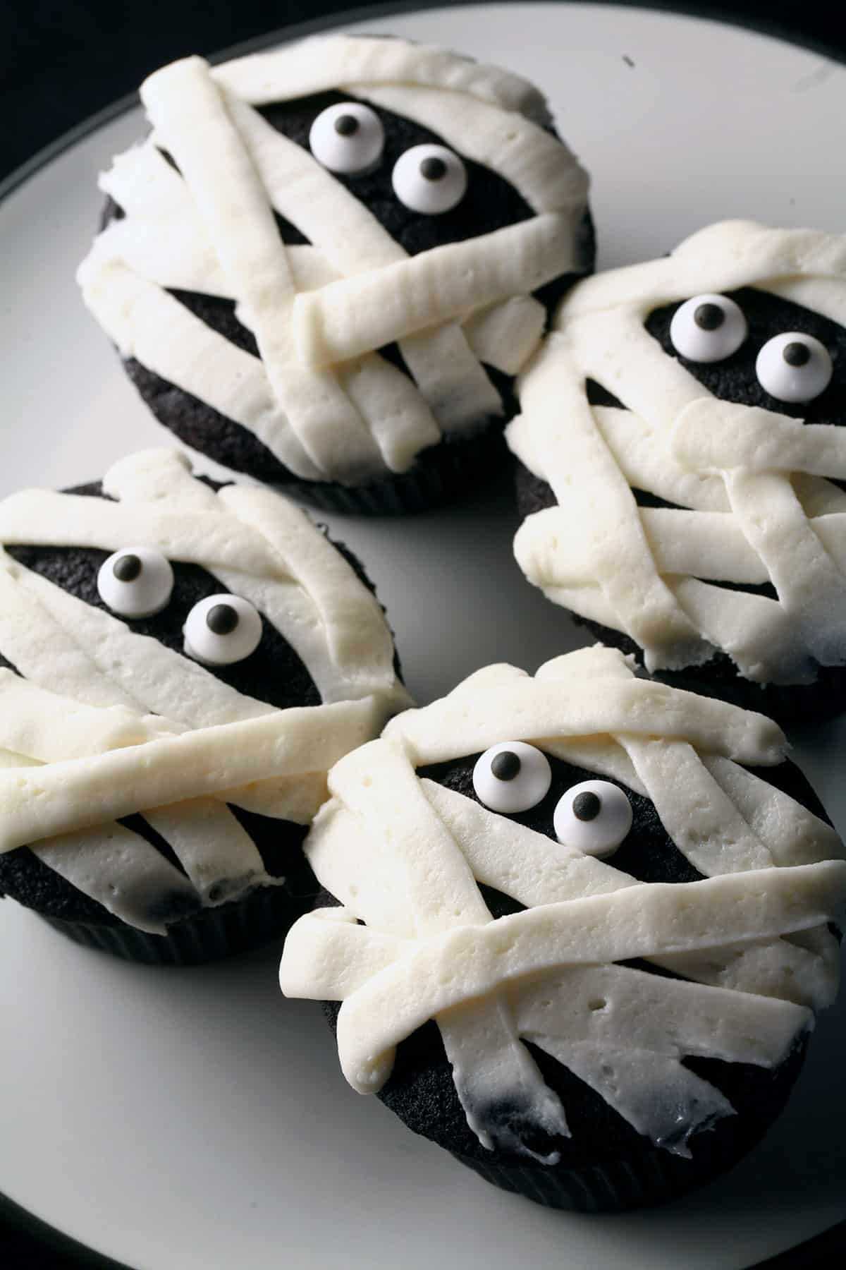 4 gluten-free black velvet cupcakes, decorated to look like mummies.