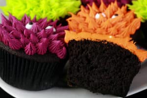 Several brightly coloured gluten free halloween cupcakes, made with gluten free black velvet cupcakes.