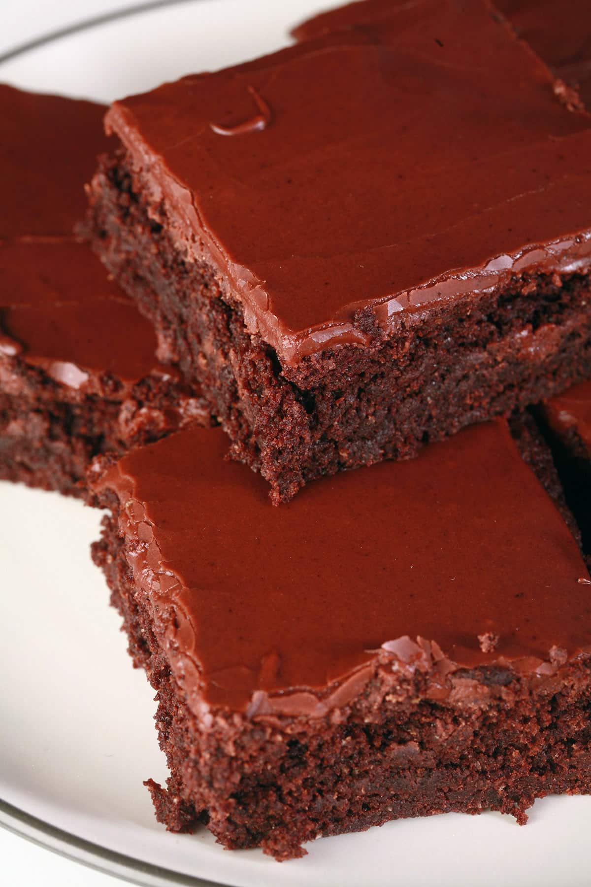 A plate of gluten free brownies with chocolate frosting.