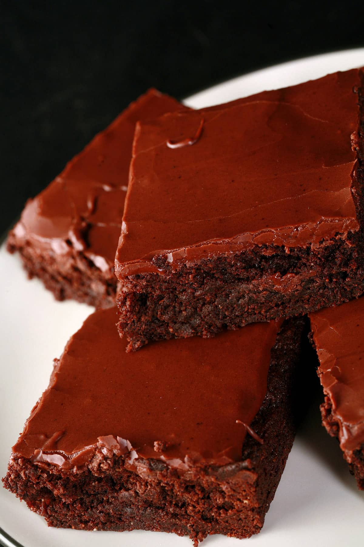 A plate of gluten-free brownies with chocolate glaze.