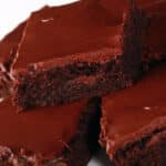 A plate of gluten-free brownies with chocolate frosting.