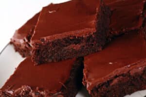 A plate of gluten-free brownies with chocolate frosting.