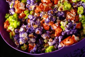 A bowl of Halloween popcorn - orange, purple, and lime green glazed popcorn, mixed together.