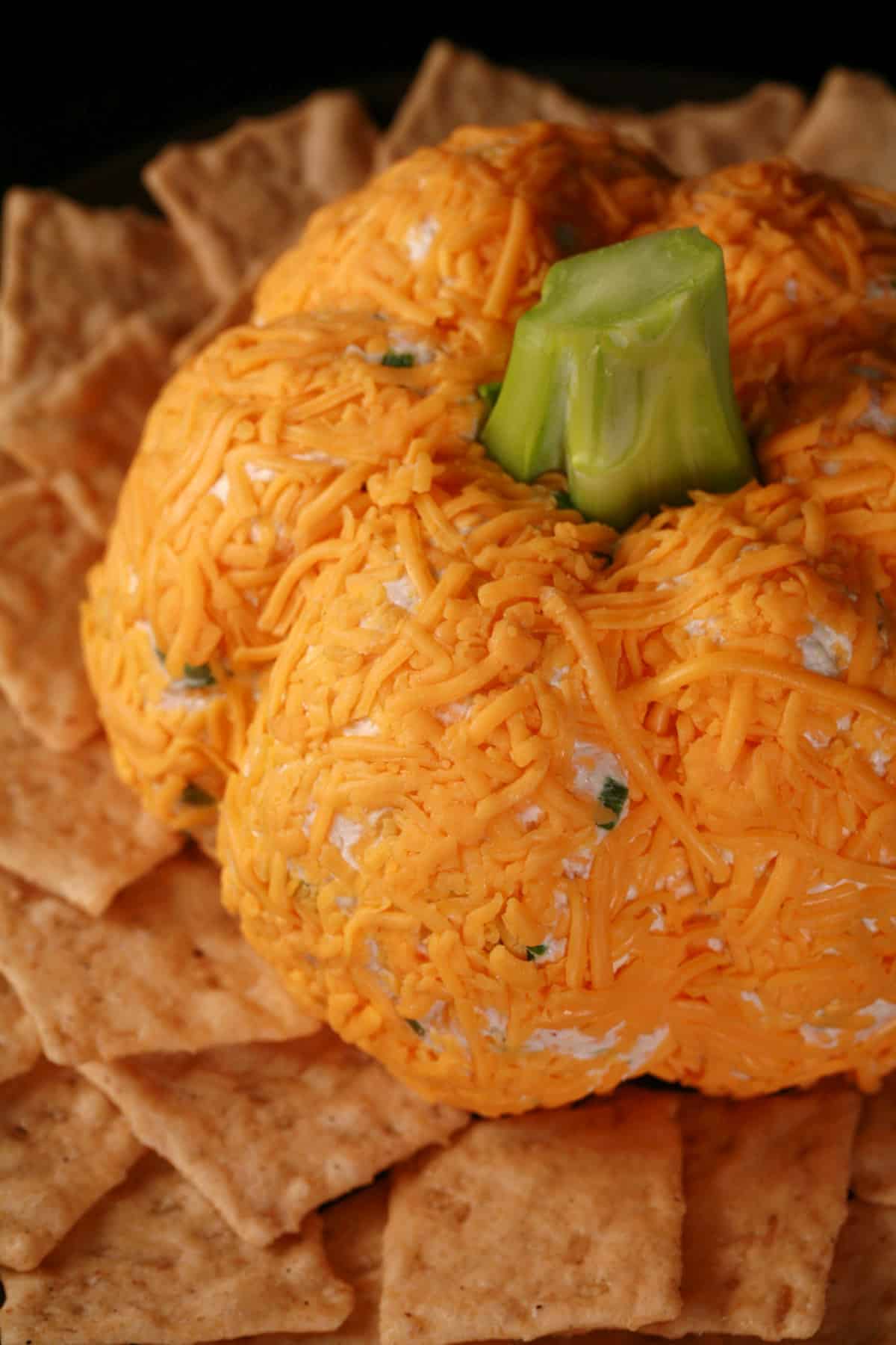 A Thanksgiving pumpkin cheese ball on a plate with crackers.