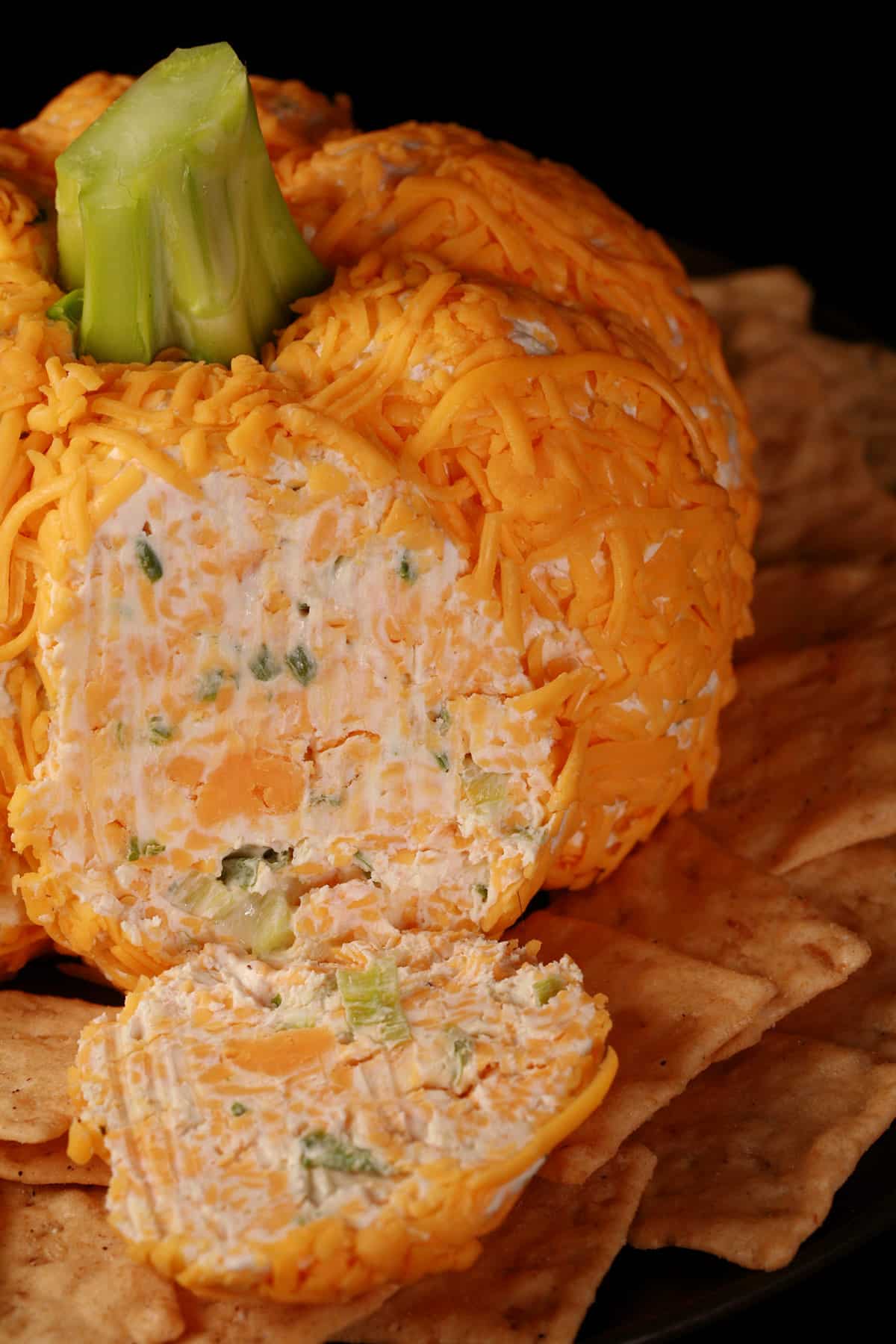 A pumpkin cheese ball with green onion visible inside.