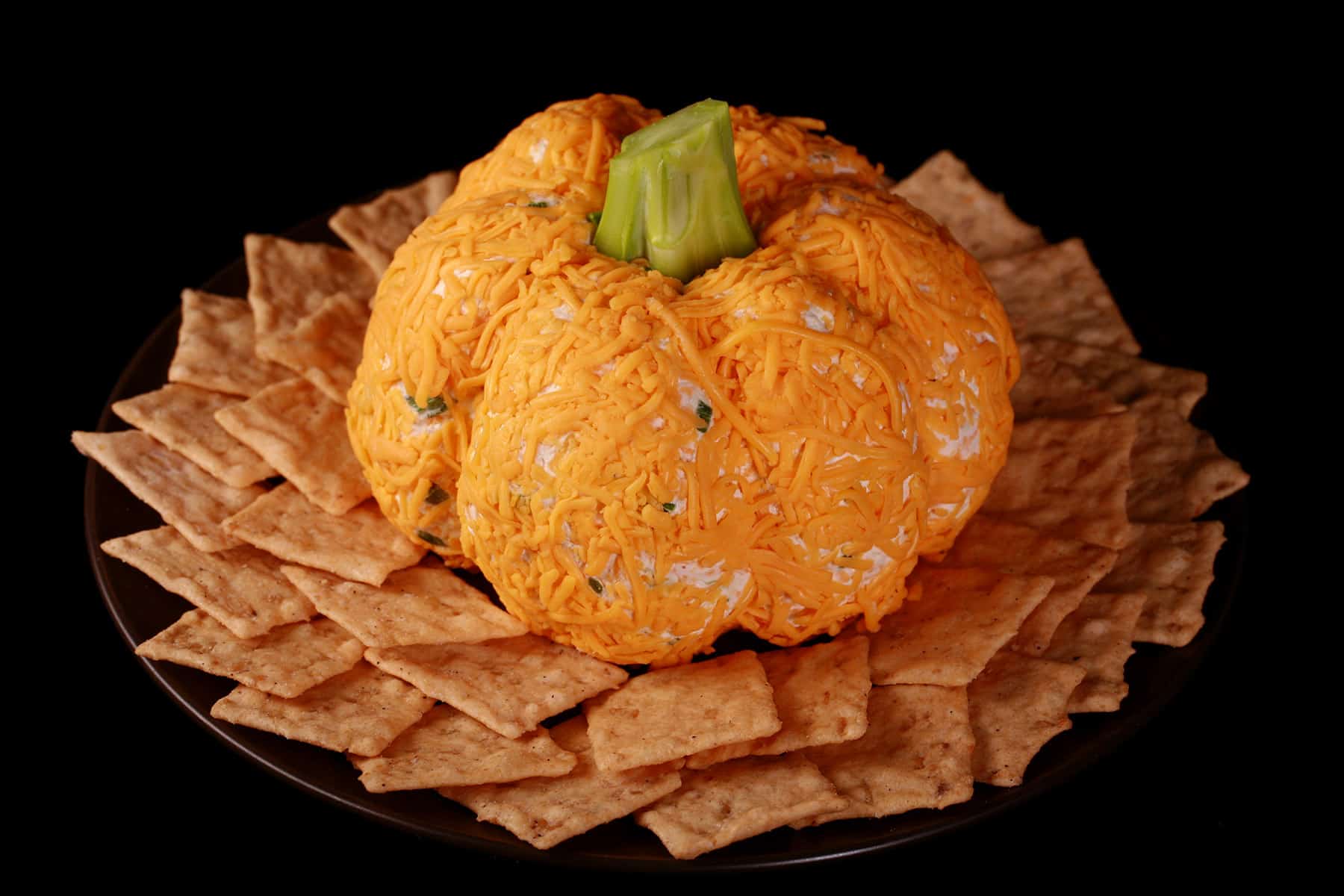 A Thanksgiving cheese ball on a plate with crackers.