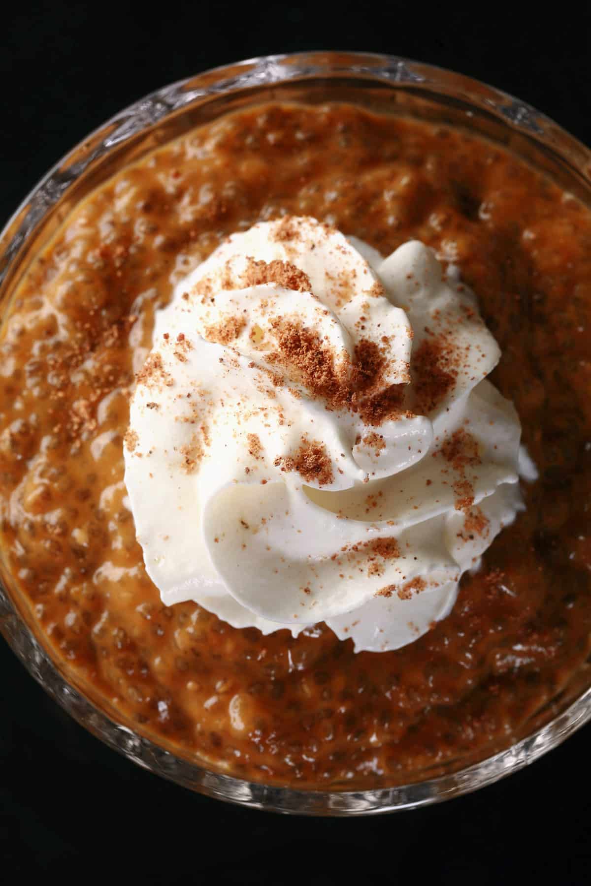 Pumpkin Chia Pudding in a glass cup, topped with whipped cream and nutmeg.
