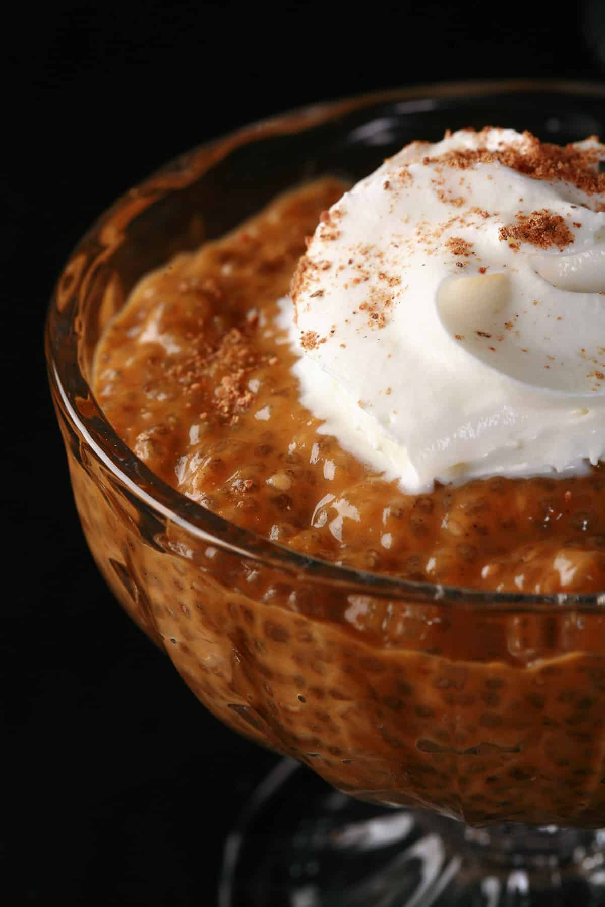Pumpkin Pie Chia Pudding in a glass cup, topped with whipped cream and nutmeg.