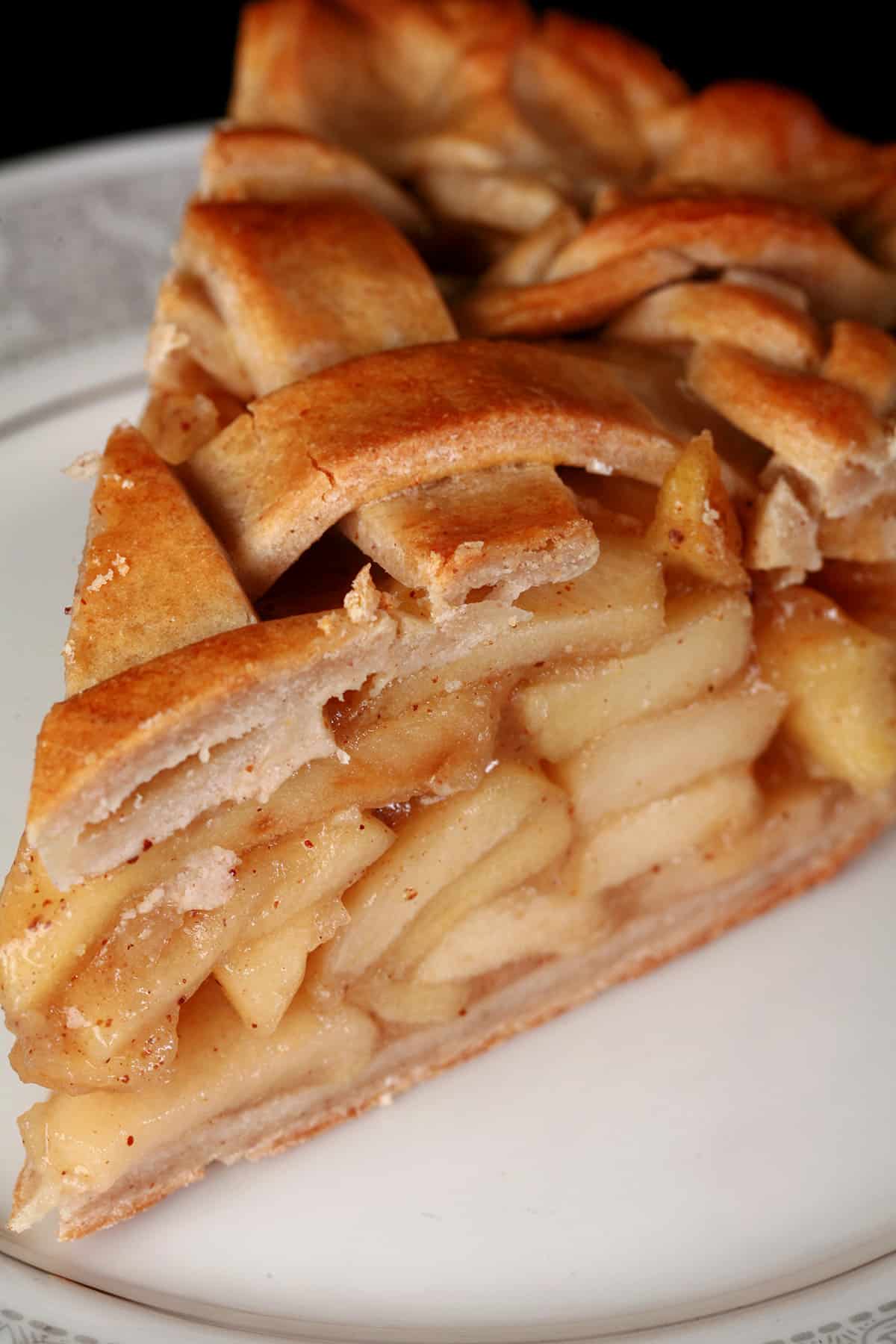 A slice of gluten free apple pie, on a white plate.