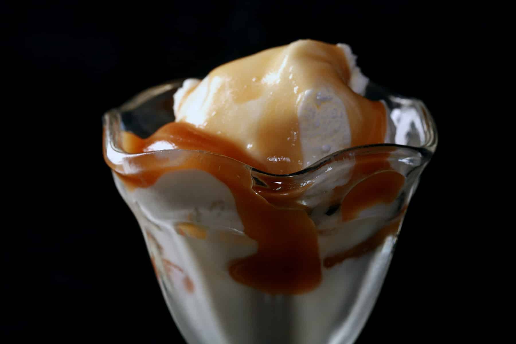 A bowl of vanilla ice cream, covered in maple caramel.