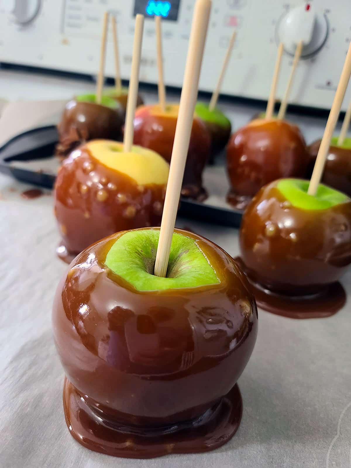 Several maple syrup caramel apples on parchment paper.
