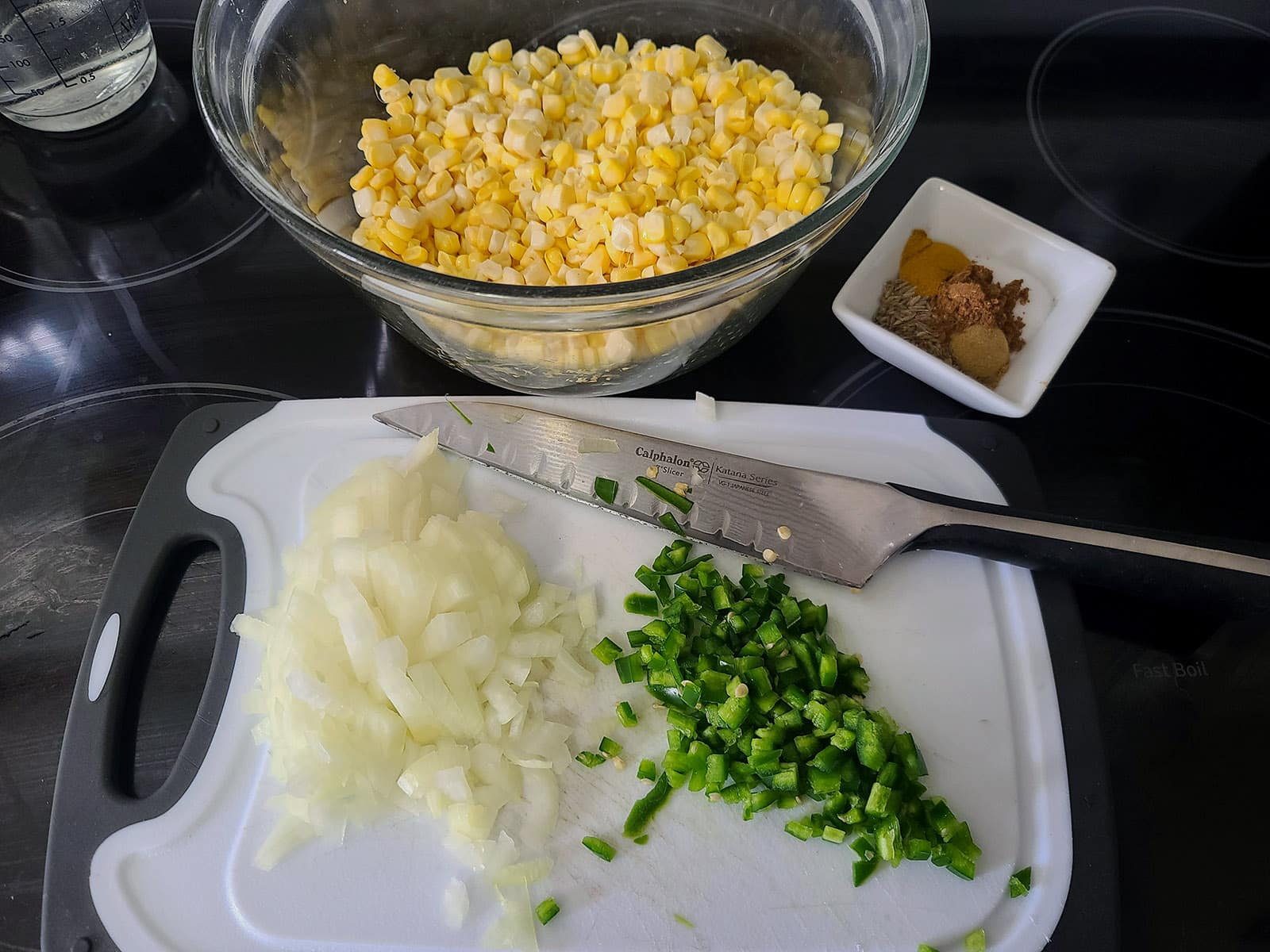 A bowl of corn and chopped up onions and peppers.
