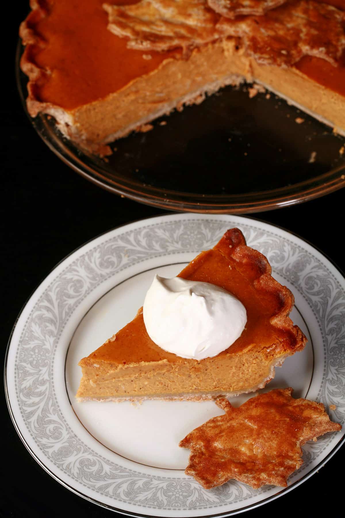 A slice of gluten-free pumpkin pie topped with maple whipped cream.