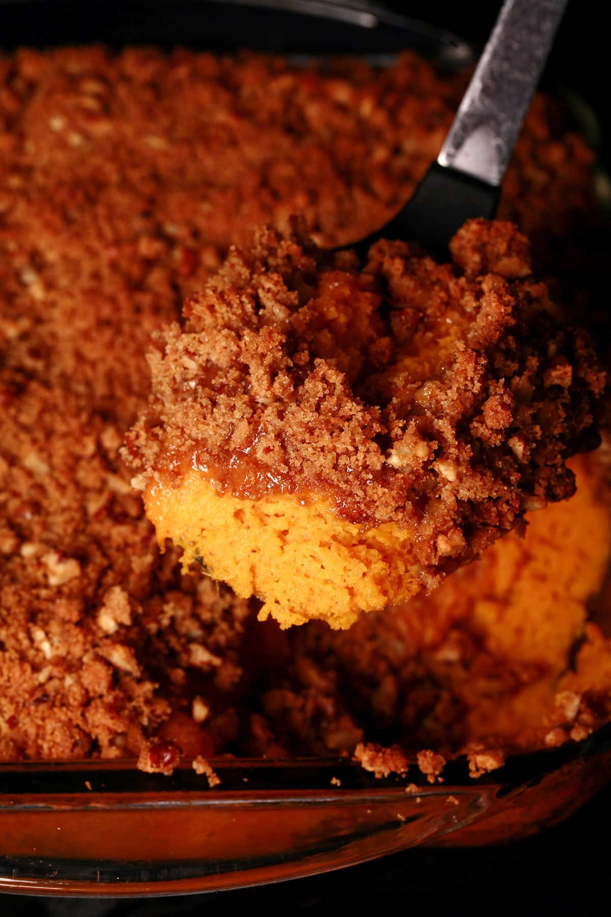A pan of sweet potato souffle with a scoop of it being spooned out.