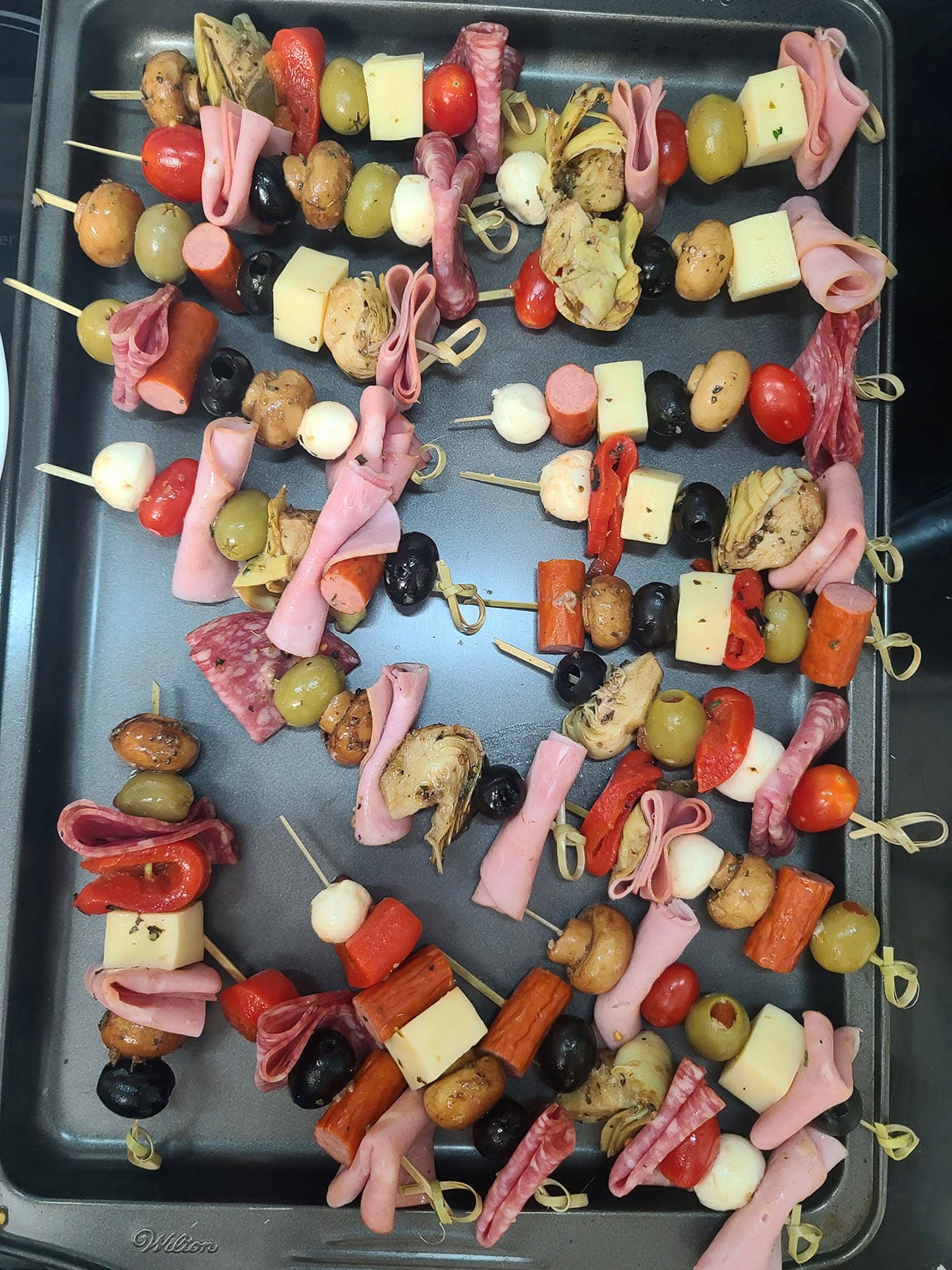 20 finished antipasto skewers on a baking pan.